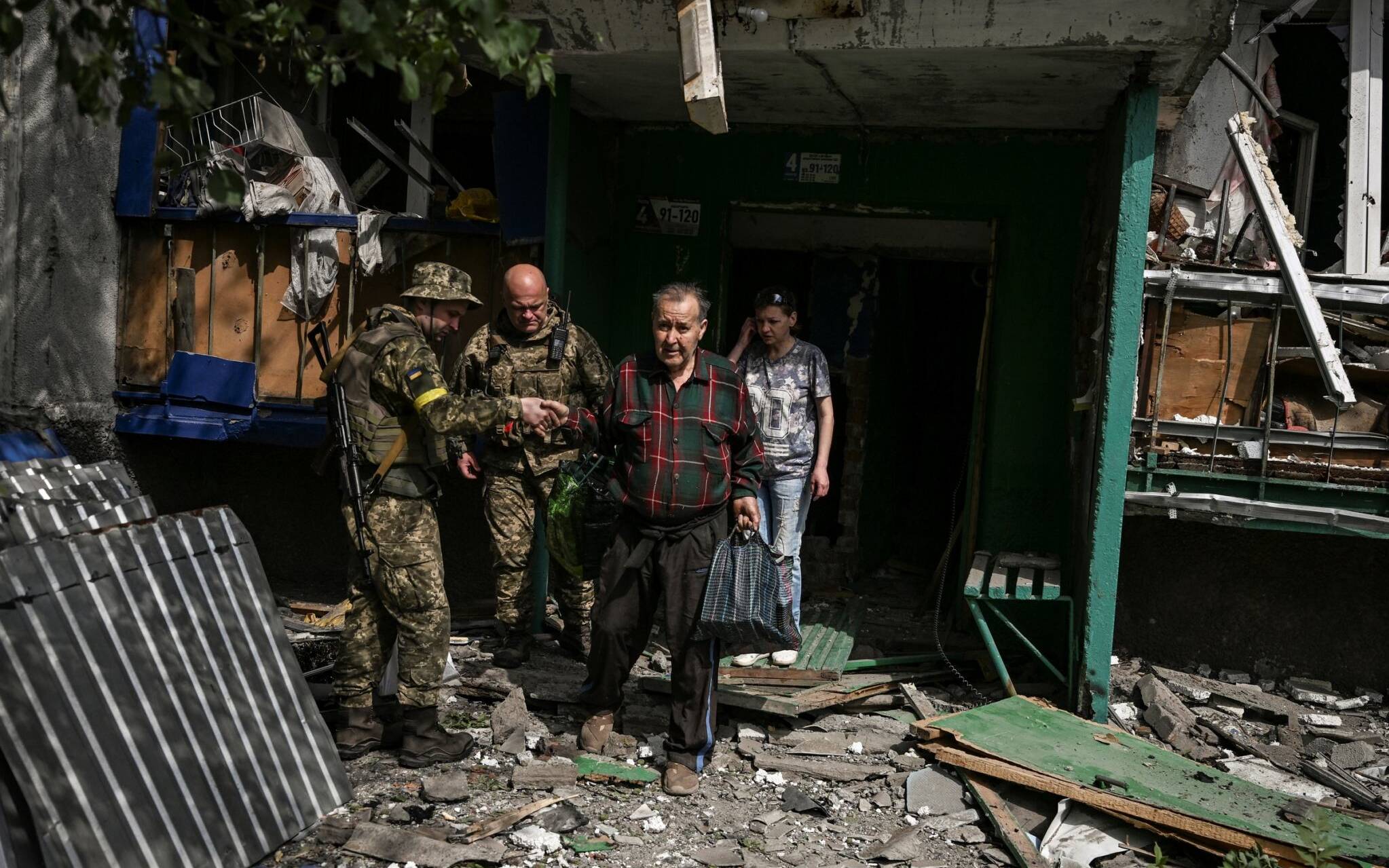Ukrainian servicemen help an elderly man to walk out of a damaged appartment building after a strike in the city of Slovyansk at the eastern Ukrainian region of Donbas on May 31, 2022, amid Russian invasion of Ukraine. (Photo by ARIS MESSINIS / AFP)