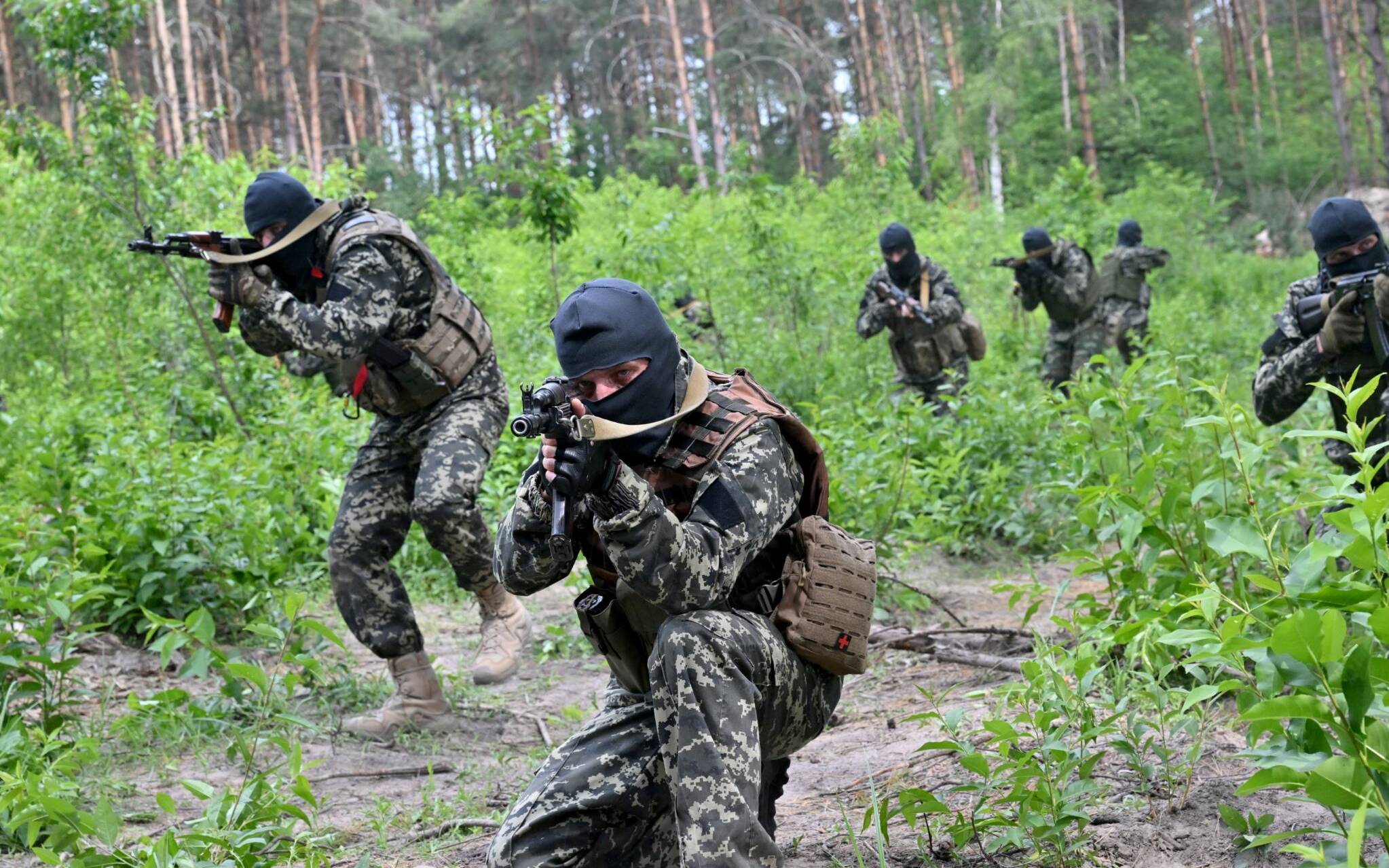 Fighters of the territorial defence unit, a support force to the regular Ukrainian army, take part in an exercise for the regular combat tactics classes, not far from the Ukrainian town of Bucha, Kyiv region on June 17, 2022. (Photo by Sergei SUPINSKY / AFP)
