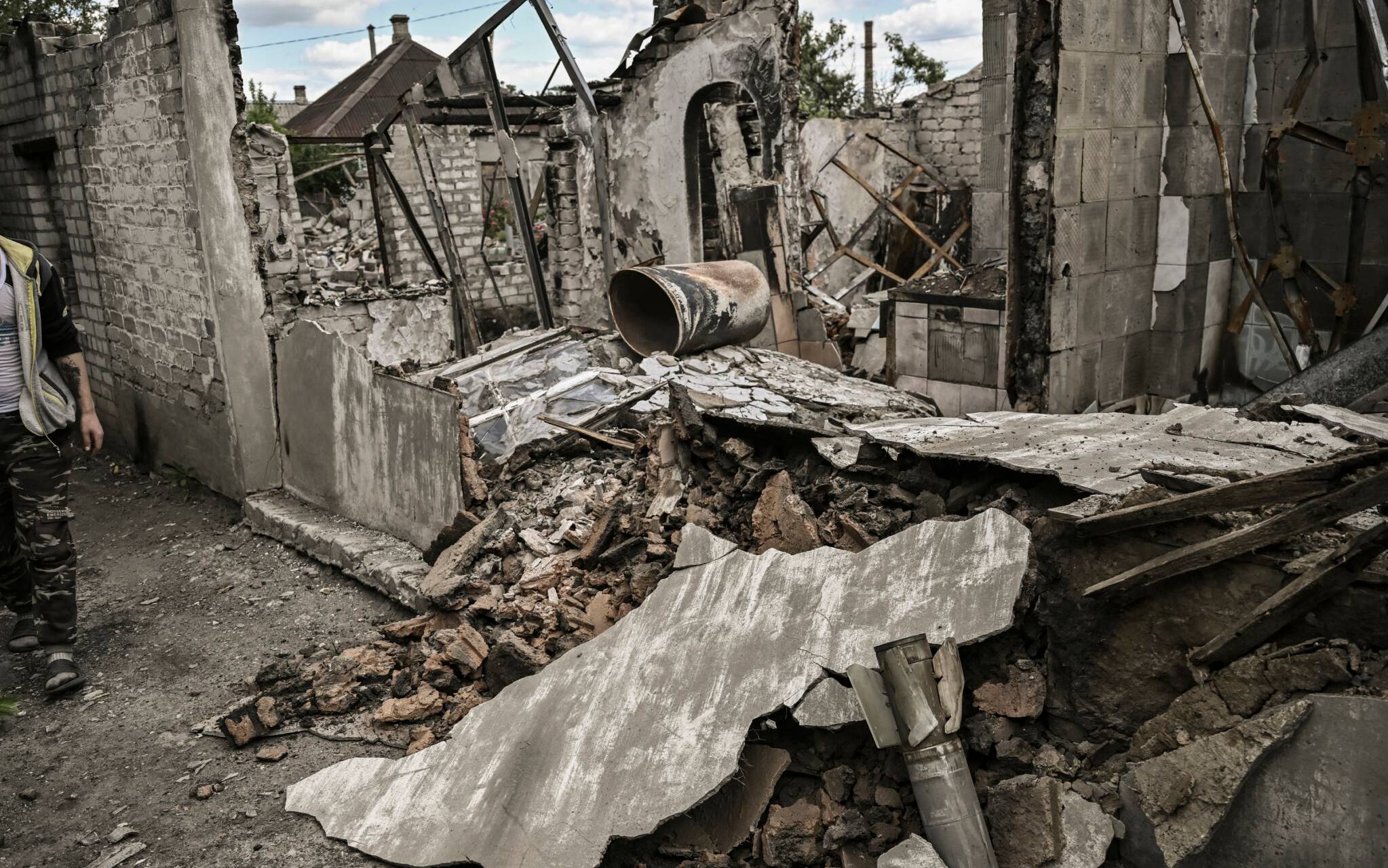 Ivan Sosnin, 19, walks next to his destroyed house in the city of Lysychansk at the eastern Ukrainian region of Donbas on June 7, 2022. (Photo by ARIS MESSINIS / AFP)