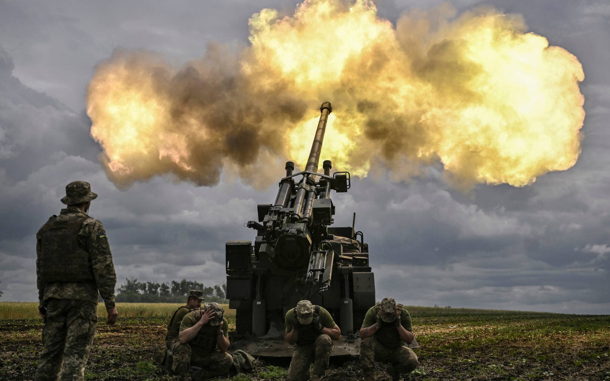 Ukrainian servicemen fire with a French self-propelled 155 mm/52-calibre gun Caesar towards Russian positions at a front line in the eastern Ukrainian region of Donbas on June 15, 2022. - Ukraine pleaded with Western governments on June 15, 2022 to decide quickly on sending heavy weapons to shore up its faltering defences, as Russia said it would evacuate civilians from a frontline chemical plant. (Photo by ARIS MESSINIS / AFP)