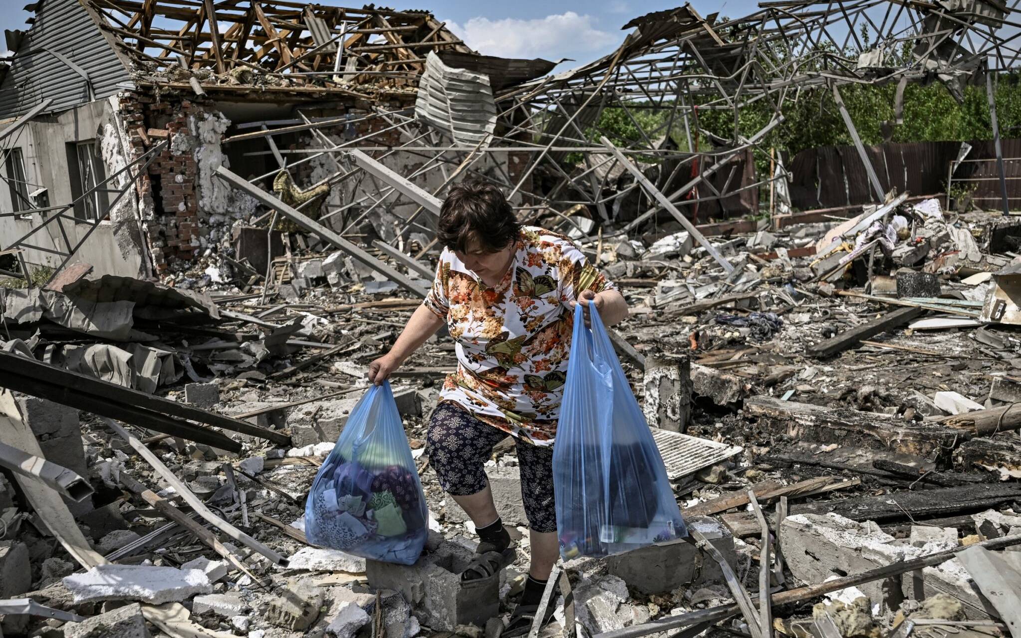 A woman collects belongings in the ruble of their house after a strike destoyed three houses in the city of Slovyansk in the eastern Ukrainian region of Donbas on June 1, 2022. (Photo by ARIS MESSINIS / AFP)