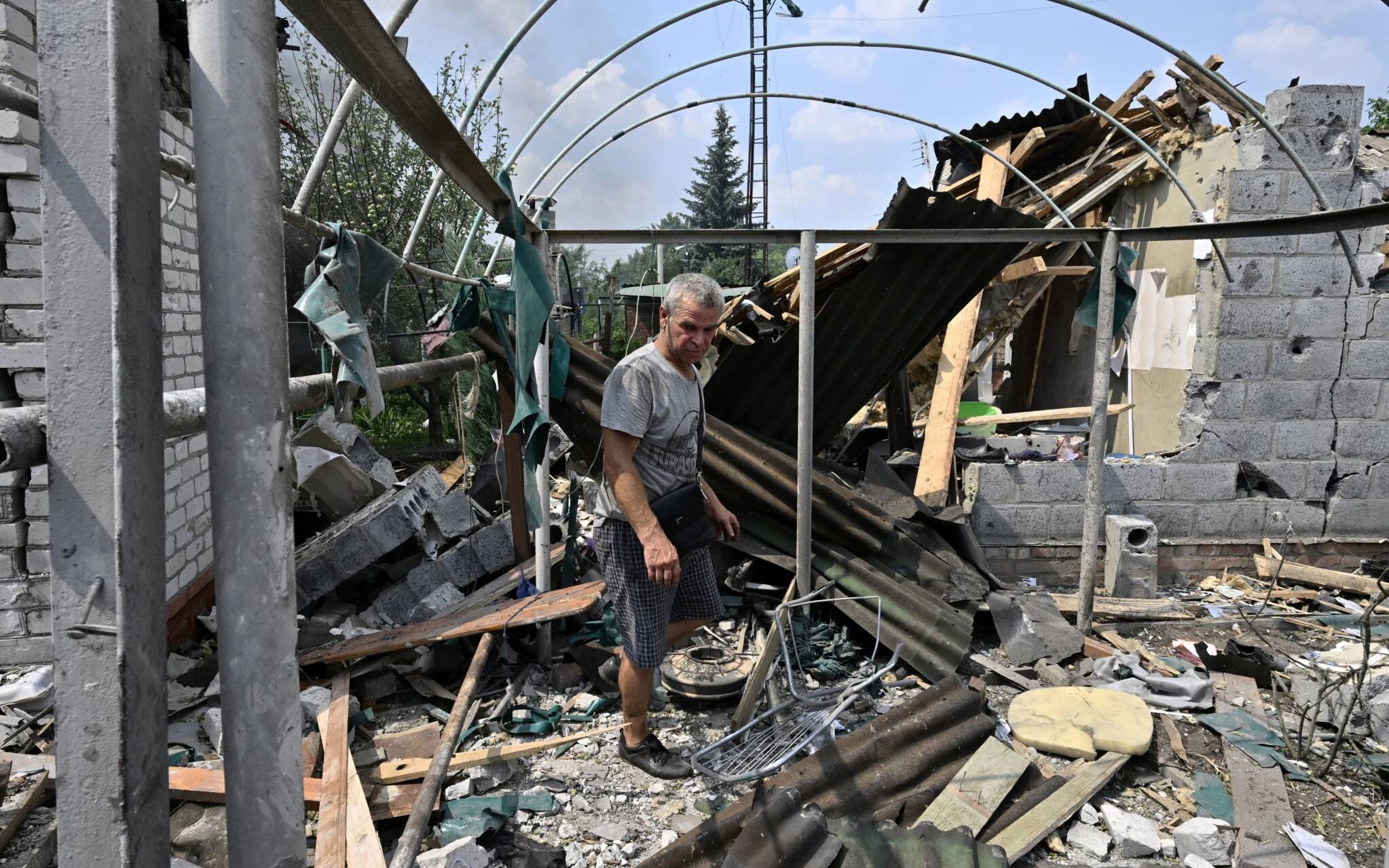 A resident walks among debris next to a destroyed house in Sloviansk on July 4, 2022, the day after a Russian rocket attack. (Photo by Genya SAVILOV / AFP)
