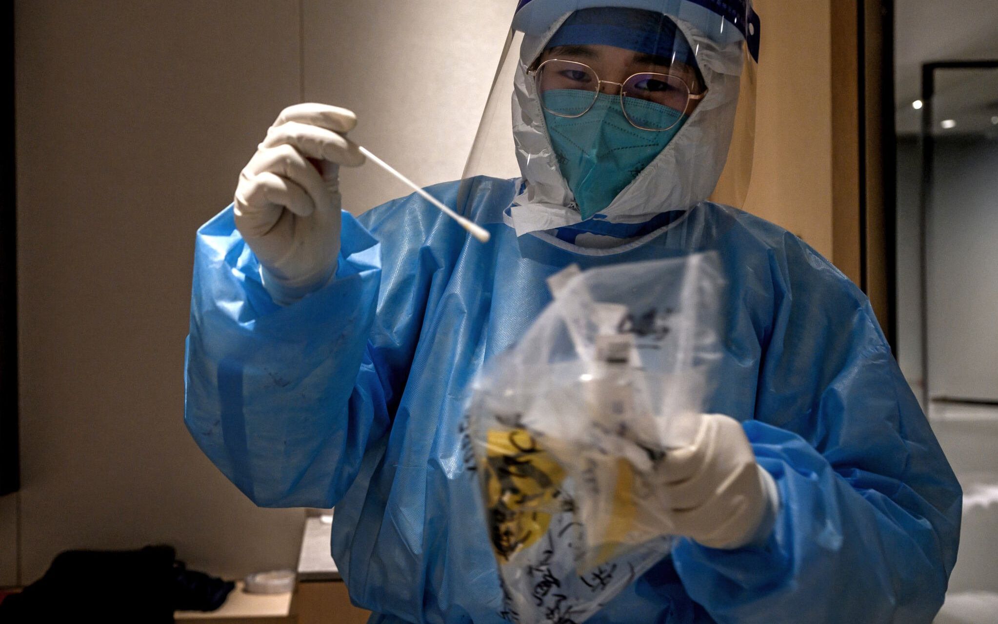 A member of the medical staff prepares to administer a Covid-19 test to a hotel guest in their room at a hotel in the Yanqing district of Beijing, on February 1, 2022, ahead of the Beijing 2022 Winter Olympic Games. (Photo by JEFF PACHOUD / AFP)