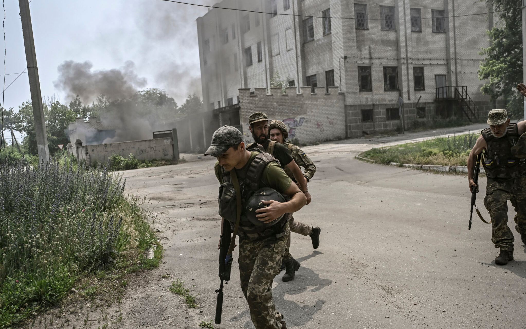 Ukrainian servicemen run for cover during an artillery duel between Ukrainian and Russian troops in the city of Lysychansk, eastern Ukrainian region of Donbas, on June 11, 2022. (Photo by ARIS MESSINIS / AFP)