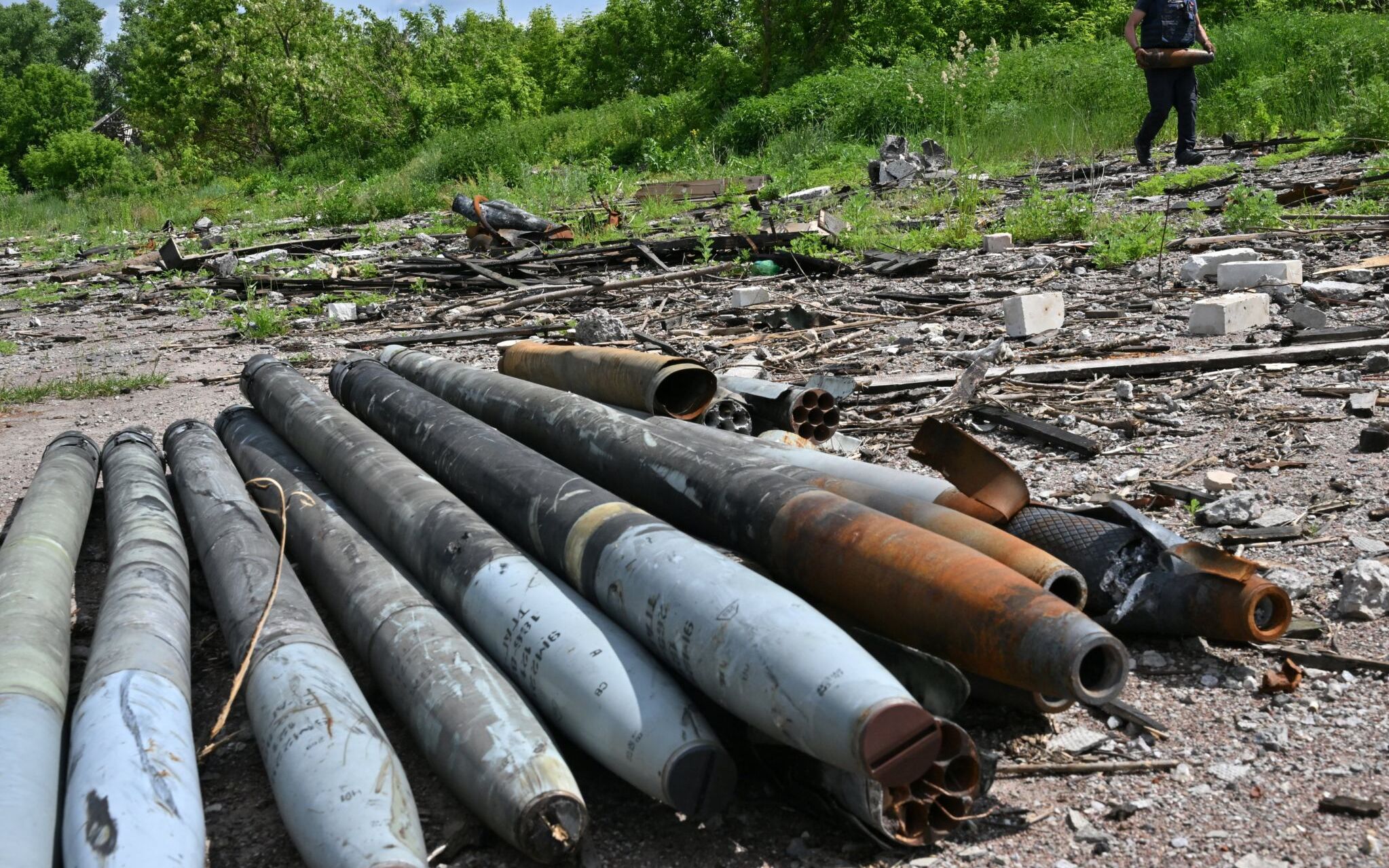 A Ukrainian bomb disposal worker carries unexploded ordnance during mine clearance work in the village of Yahidne, in the liberated territories of the Chernihiv region on June 7, 2022 amid the Russian invasion of Ukraine. (Photo by Sergei SUPINSKY / AFP)