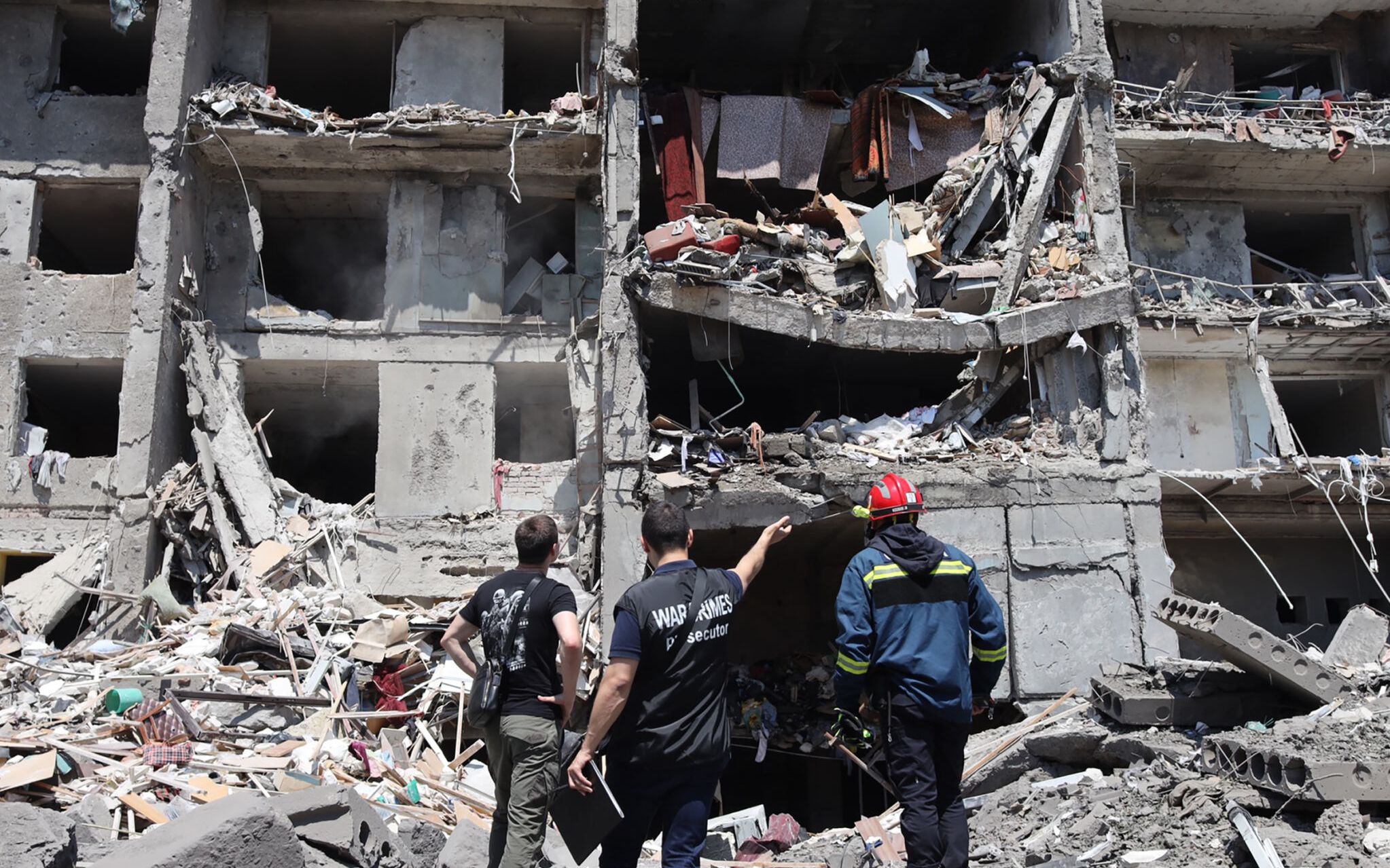 A war crimes prosecutor (C) and a rescuer (R) and a civil,  look at a destroyed building after being hit by a missile strike in the Ukrainian town of Sergiyvka , near Odessa, killing at least 18 people and injuring 30, on July 1, 2022. - During the night from June 30 to July 1, 2022, two missiles were fired by a "strategic aircraft" from the Black Sea, hitting buildings, according to the Ukrainian emergency services. (Photo by Oleksandr GIMANOV / AFP)