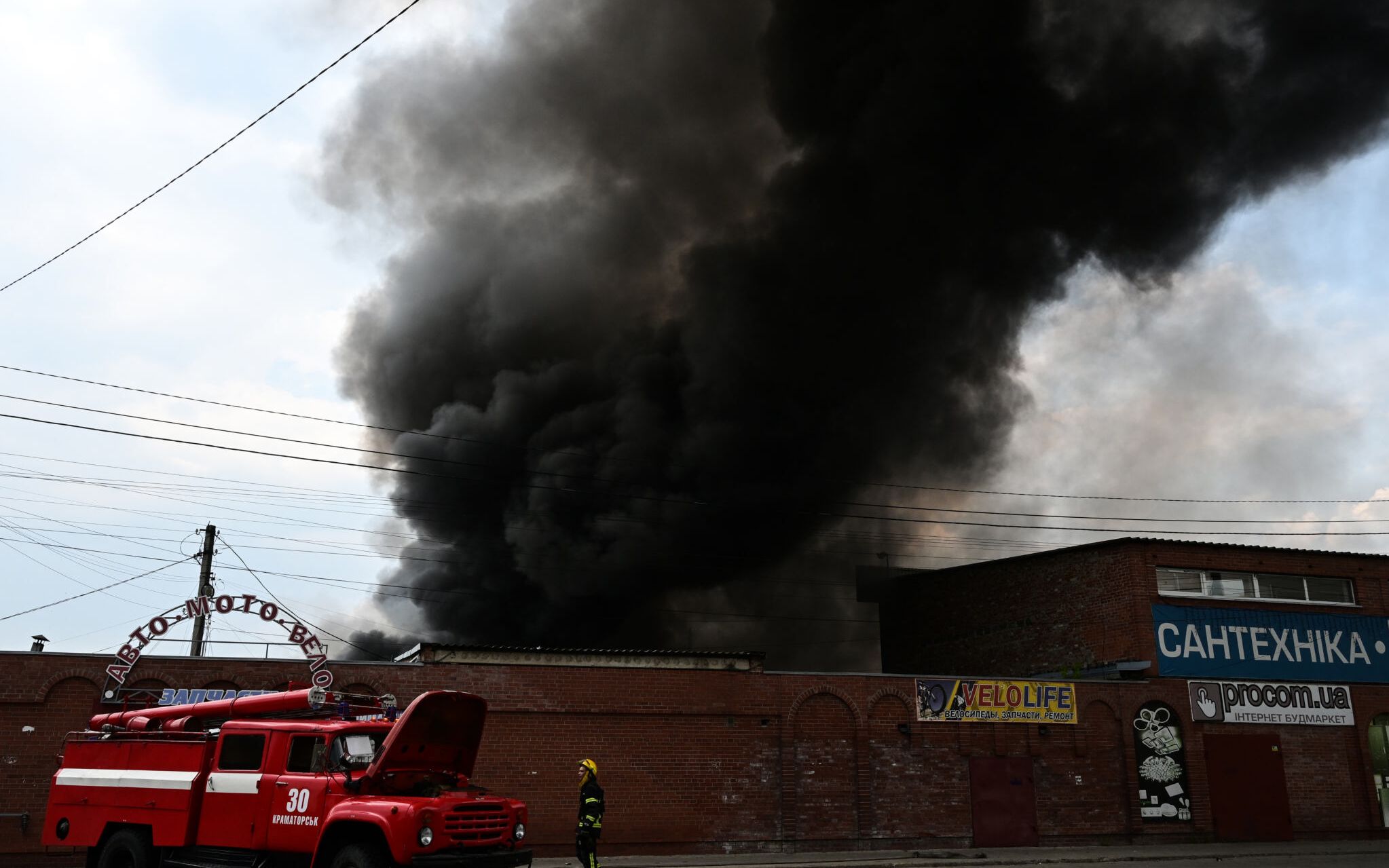 Firefighters work to control flames at the central market of Sloviansk on July 5, 2022, following a suspected missile attack amid the Russian invasion of Ukraine. (Photo by MIGUEL MEDINA / AFP)