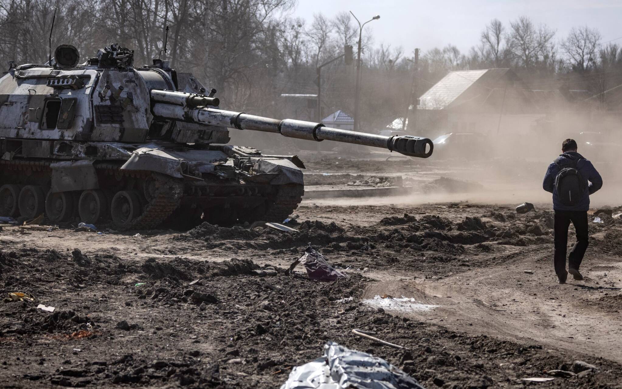 A resident walks near a damaged Russian tank in the northeastern city of Trostyanets', on March 29, 2022. - Ukraine said on March 26, 2022 its forces had recaptured the town of Trostyanets, near the Russian border, one of the first towns to fall under Moscow's control in its month-long invasion. (Photo by FADEL SENNA / AFP)