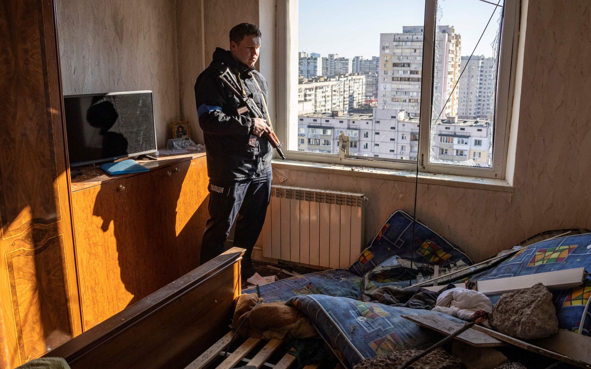 A police officer looks through the window of a damaged flat in a residential building which was hit by the debris from a downed rocket in Kyiv on March 17, 2022. - One person was killed and three injured when debris from a downed rocket hit a Kyiv apartment block, as Russian forces press in on the capital, emergency services said. Russian troops trying to encircle Kyiv have launched early morning strikes on the city for several successive days, putting traumatised residents further on edge. (Photo by FADEL SENNA / AFP)