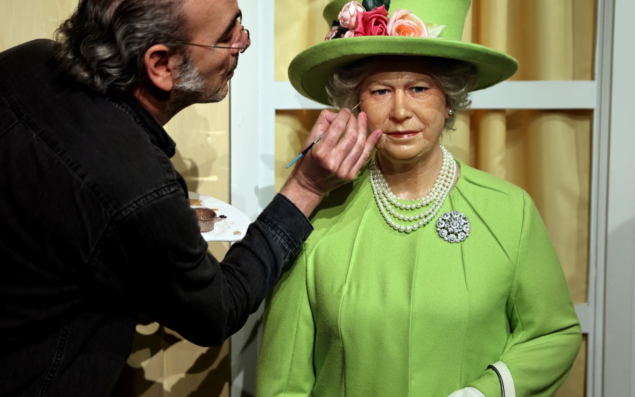 An artist renovate the wax statue of British Queen Elisabeth II at the Musee Grevin in Paris on June 2, 2022, as Britain celebrates the Queen's platinum jubilee. (Photo by Thomas COEX / AFP)