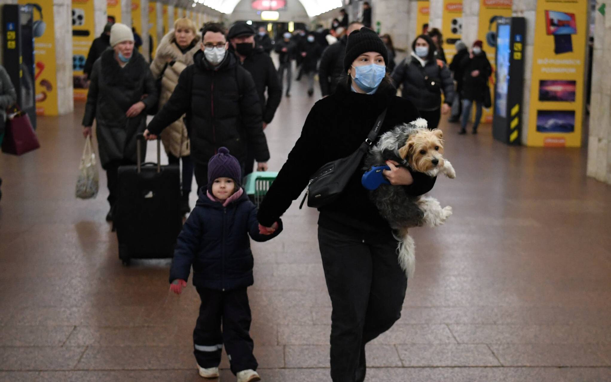 A woman with a child and a dog walks at a metro station in Kyiv early on February 24, 2022. - Russian President Vladimir Putin announced a military operation in Ukraine on Thursday with explosions heard soon after across the country and its foreign minister warning a "full-scale invasion" was underway. (Photo by Daniel LEAL / AFP)