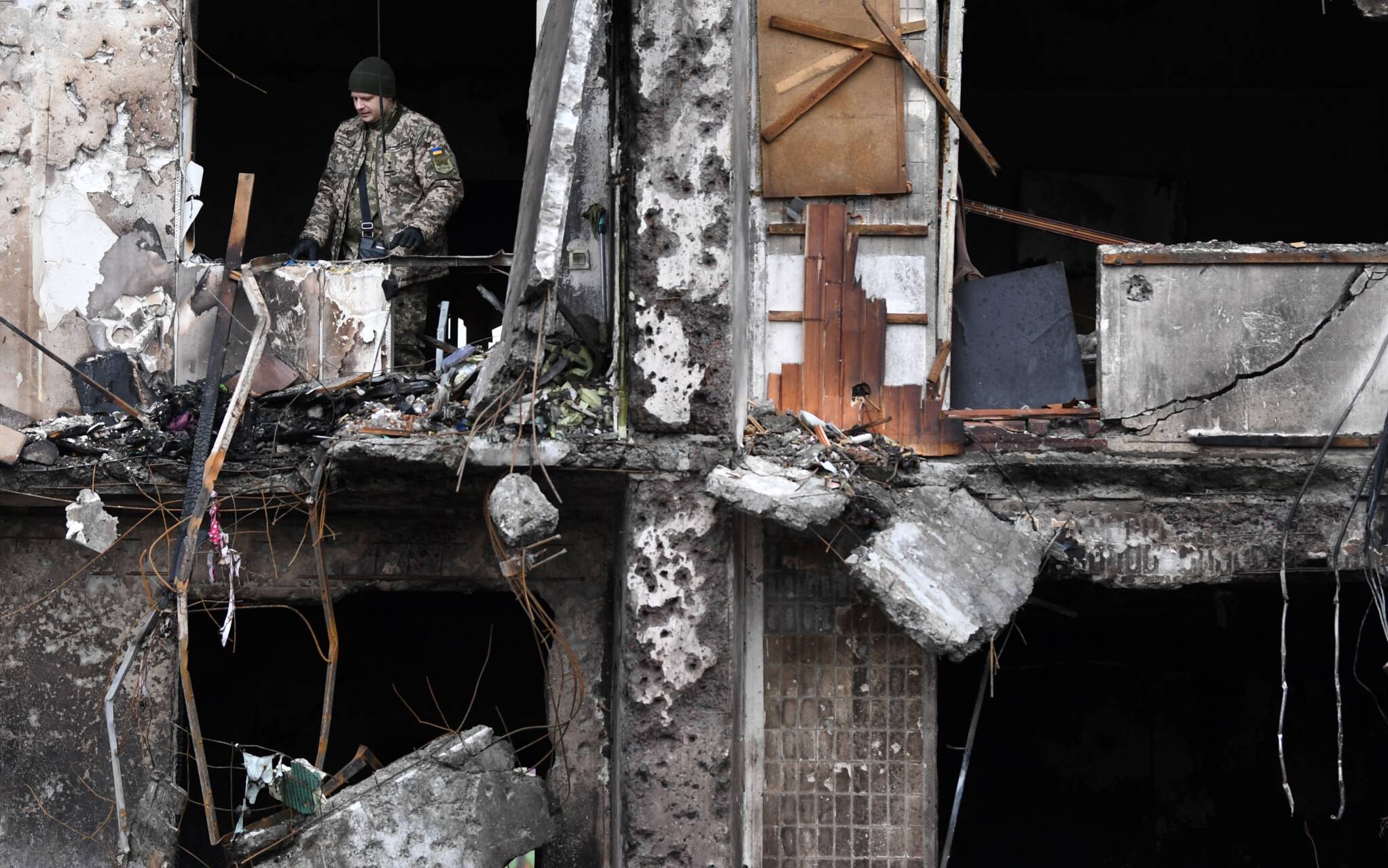 A Ukrainian serviceman is seen in the window of a damaged residential building at Koshytsa Street, a suburb of the Ukrainian capital Kyiv, where a military shell allegedly hit, on February 25, 2022. - Russian forces reached the outskirts of Kyiv on Friday as Ukrainian President Volodymyr Zelensky said the invading troops were targeting civilians and explosions could be heard in the besieged capital. Pre-dawn blasts in Kyiv set off a second day of violence after Russian President Vladimir Putin defied Western warnings to unleash a full-scale ground invasion and air assault on Thursday that quickly claimed dozens of lives and displaced at least 100,000 people. (Photo by Daniel LEAL / AFP)