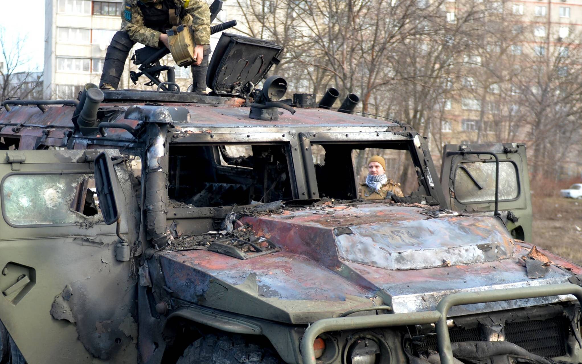 An Ukrainian Territorial Defence fighter examines a destroyed Russian infantry mobility vehicle GAZ Tigr after the fight in Kharkiv on February 27, 2022. - Ukrainian forces secured full control of Kharkiv on February 27, 2022 following street fighting with Russian troops in the country's second biggest city, the local governor said. (Photo by Sergey BOBOK / AFP)