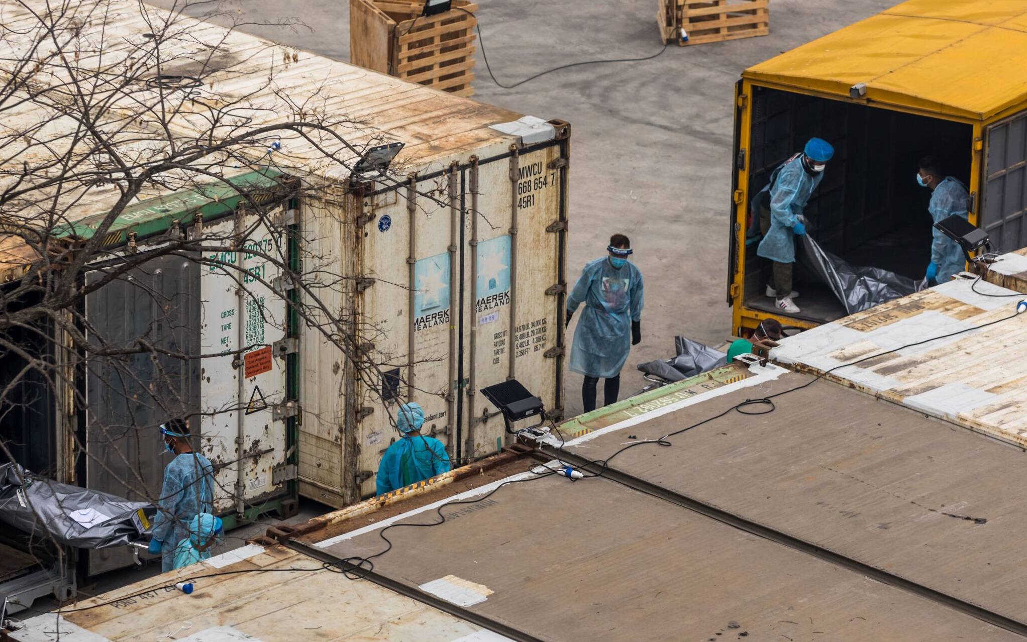 Workers move the bodies of deceased people from a truck into a refrigerated container at the Fu Shan Public Mortuary in Hong Kong on March 16, 2022, amid the city's worst-ever Covid-19 coronavirus outbreak that has seen overflowing hospitals and morgues and a frantic expansion of the city's spartan quarantine camp system. (Photo by DALE DE LA REY / AFP)