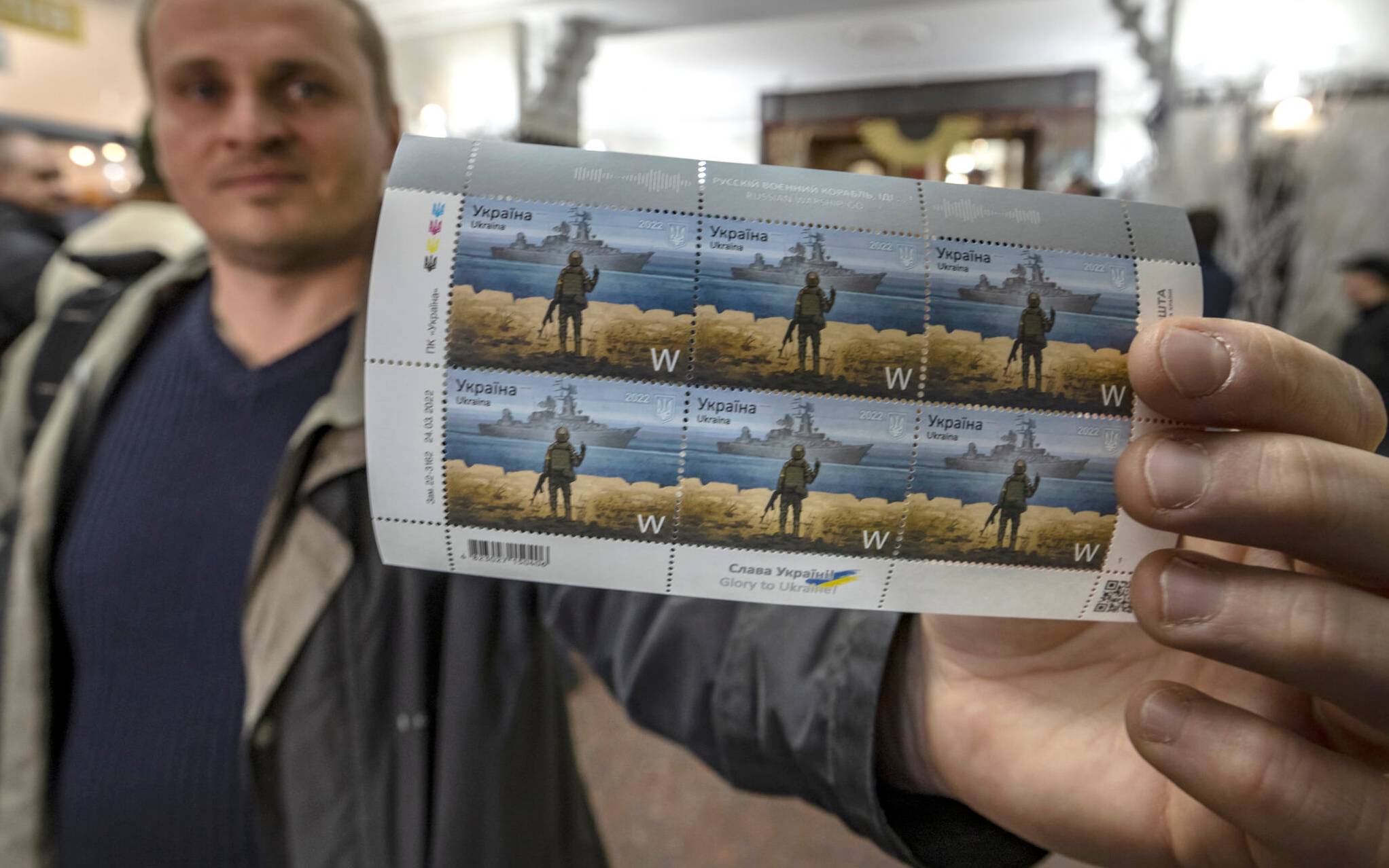A local resident shows new Ukrainian stamps titled "Russian warship, Go...!" at a post office in the center of Kyiv on April 15, 2022. (Photo by FADEL SENNA / AFP)