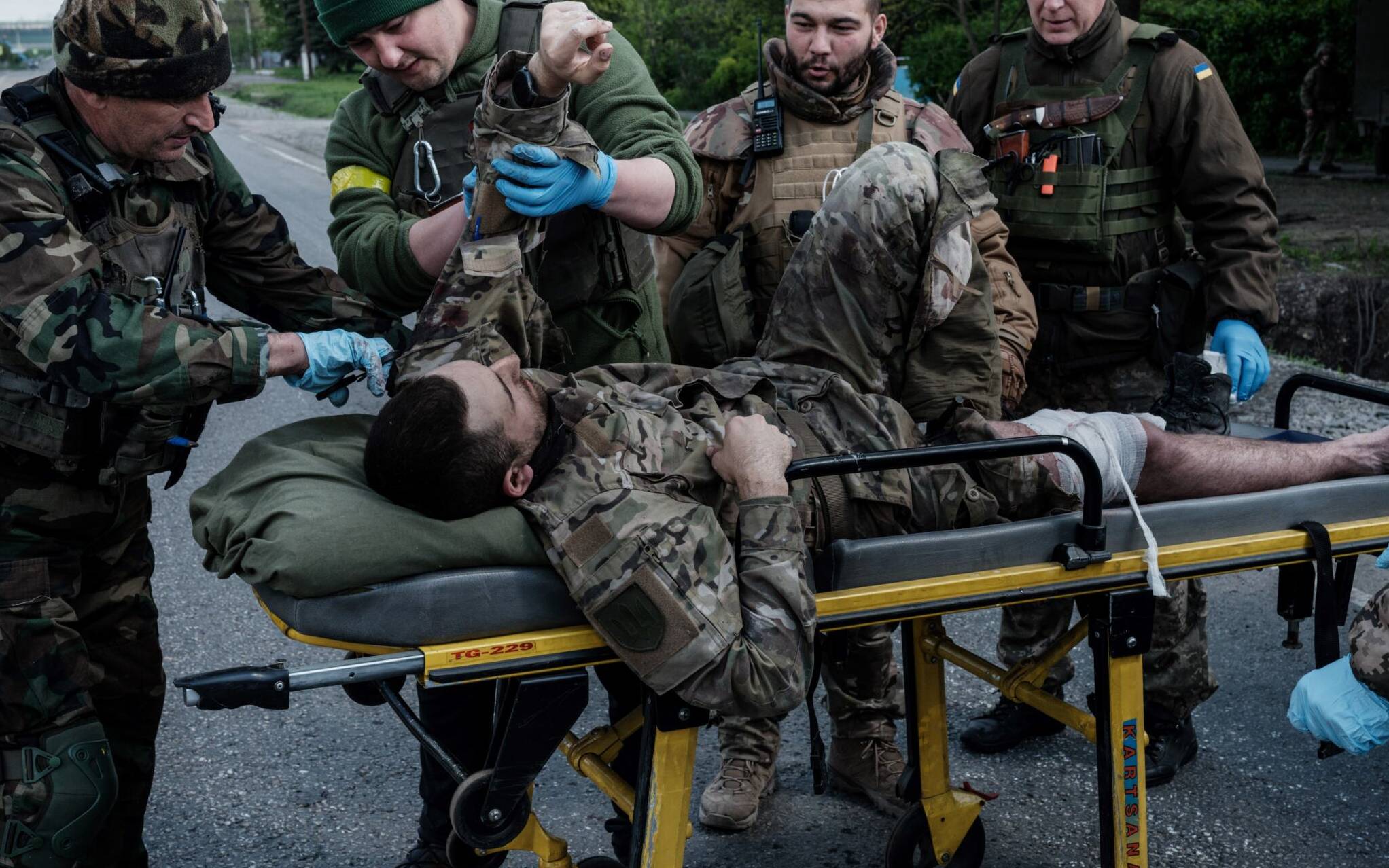 Members of the Ukrainian Army's mobile evacuation unit treat a wounded soldier before his transfer to a hospital by ambulance, on a road near Lysychansk, eastern Ukraine, on May 10, 2022, amid the Russian invasion of Ukraine. (Photo by YASUYOSHI CHIBA / AFP)