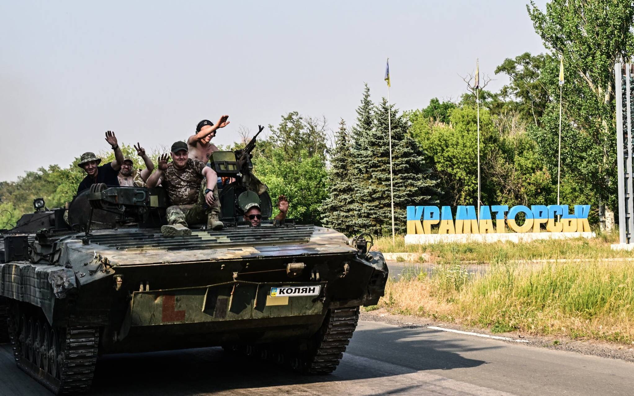 Ukrainian soldiers on the top of a Ukrainian armoured fighting vehicle gesture as they drive down at the exit of Kramatorsk, eastern Ukraine, on July 6, 2022, amid the Russian invasion of Ukraine. (Photo by MIGUEL MEDINA / AFP)