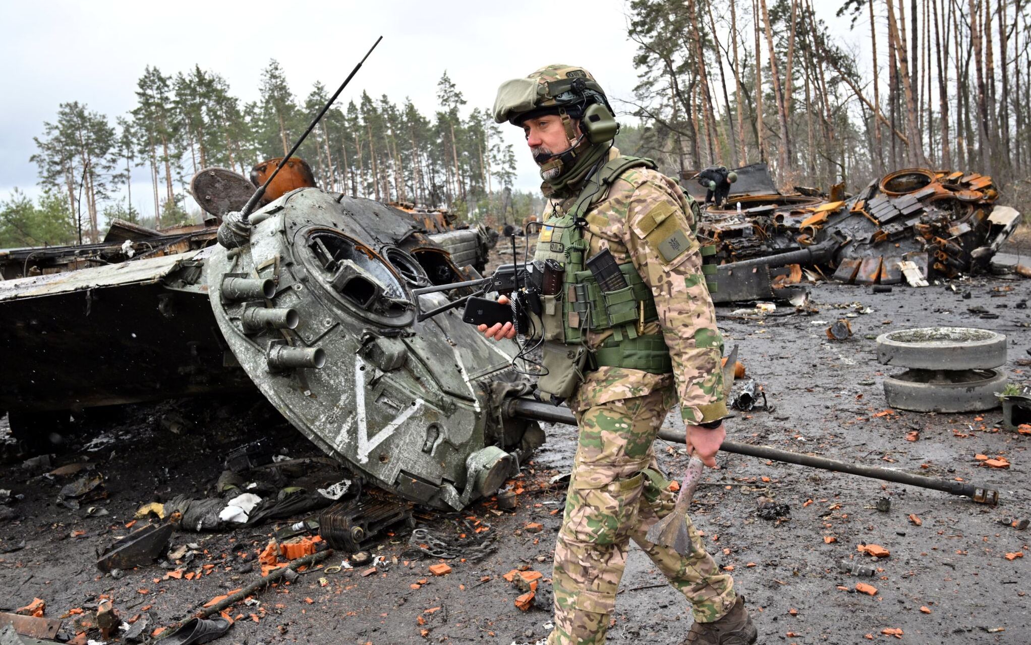 A Ukrainian serviceman walks past destroyed Russian tanks not far from the Ukrainian capital of Kyiv on April 3, 2022. - Europe's worst conflict in decades, sparked by Russia's invasion on February 24, has already left some 20,000 people dead, according to Ukrainian estimates. (Photo by Sergei SUPINSKY / AFP)
