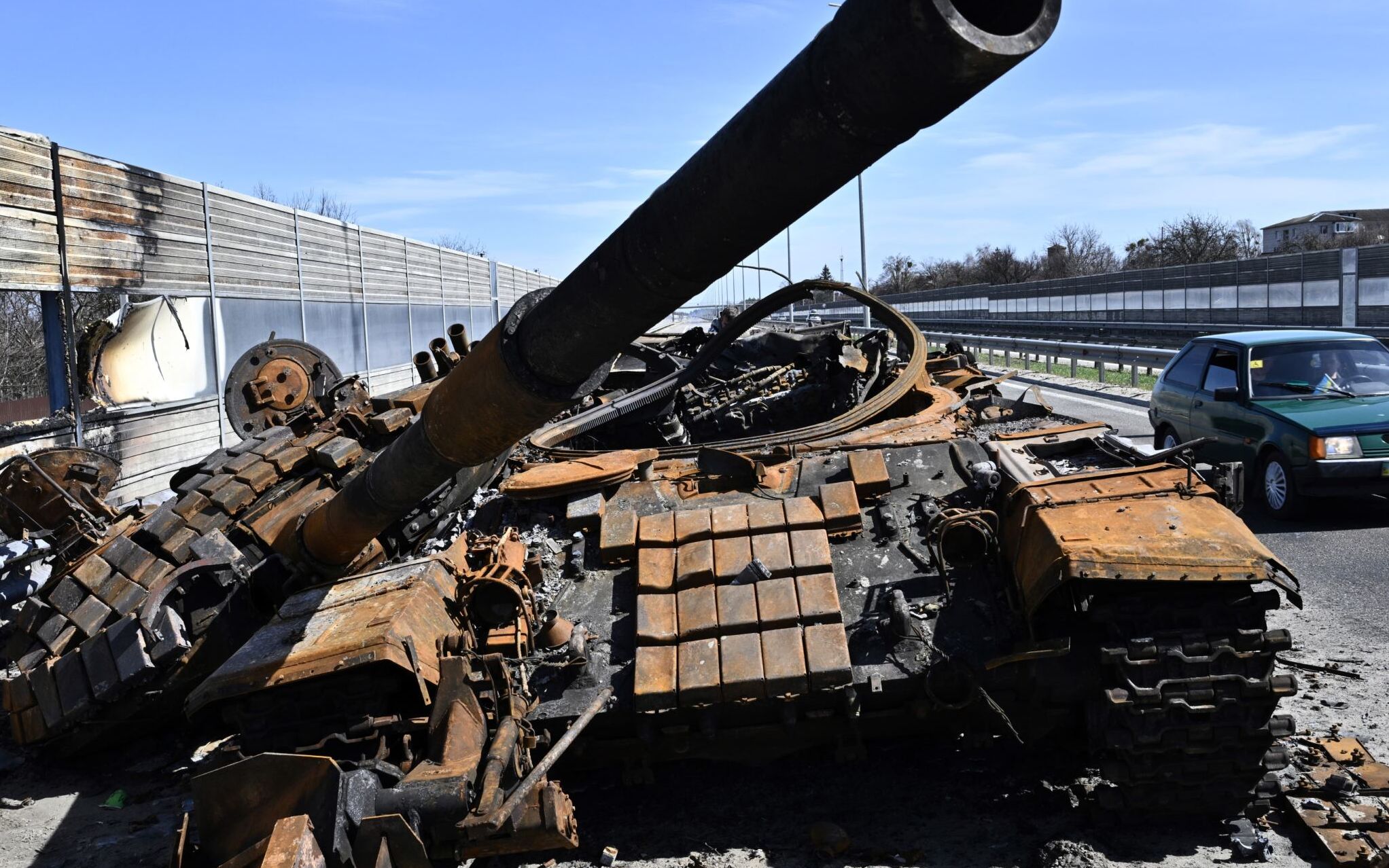 A car drives past a burnt Russian tank  on a road west of Kyiv, on April 7, 2022, during Russia's military invasion launched on Ukraine. - Six weeks after Russia invaded its neighbour, its troops have withdrawn from Kyiv and Ukraine's north and are focusing on the country's southeast, where desperate attempts are under way to evacuate civilians. (Photo by Genya SAVILOV / AFP)