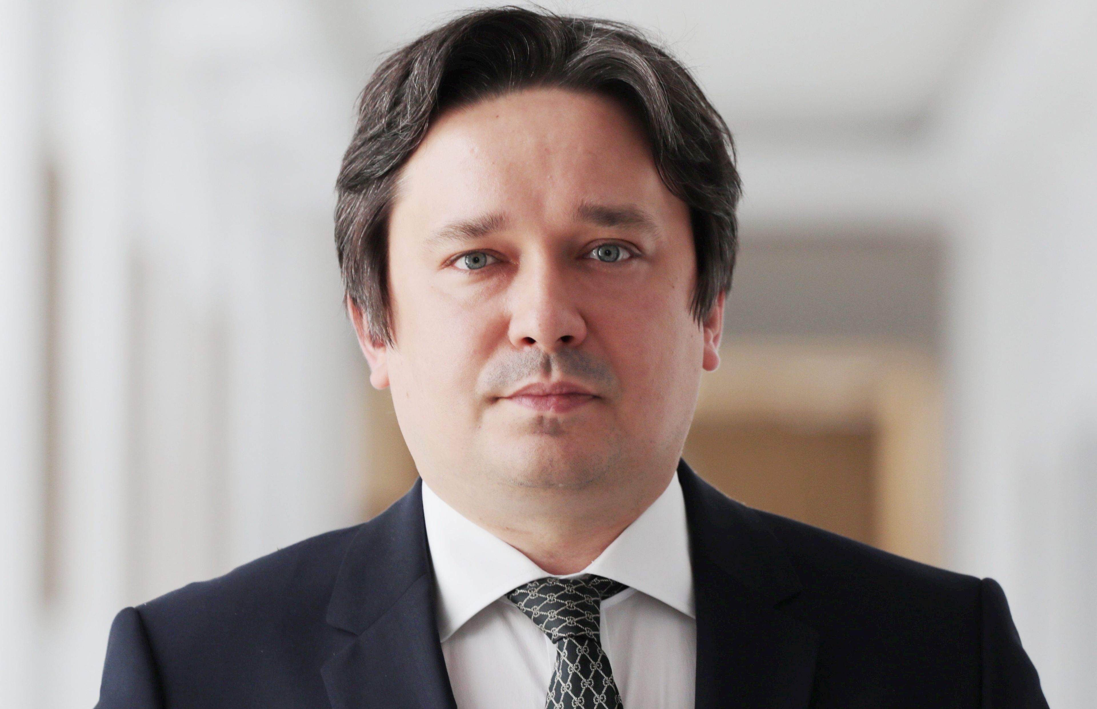 40-letni brunet w ciemnym garniturze i białej koszuli