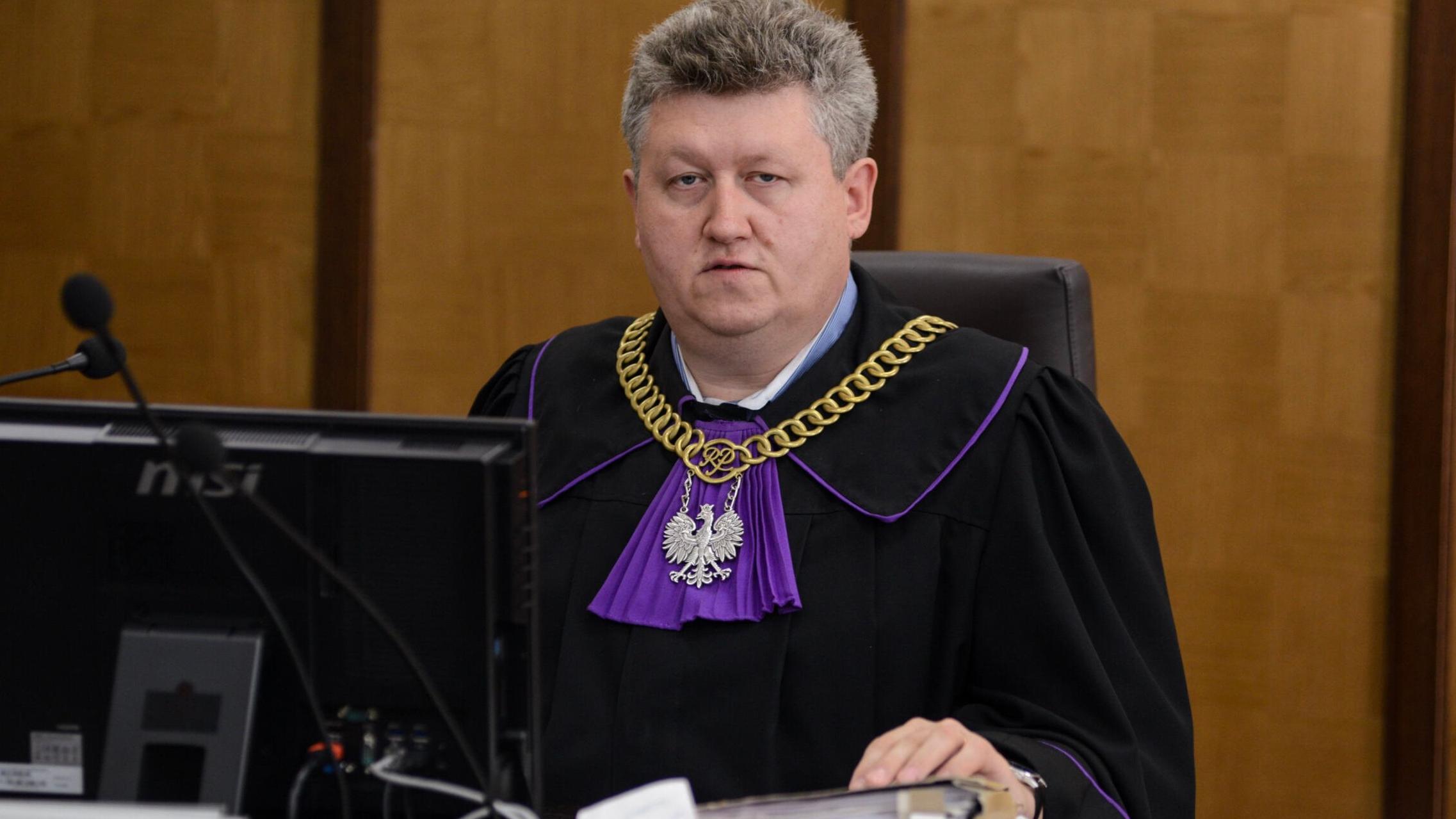 sędzia Krzysztof Chmielewski w todze i z łańcuchem sędziowskim prowadzi rozprawę w sądzie