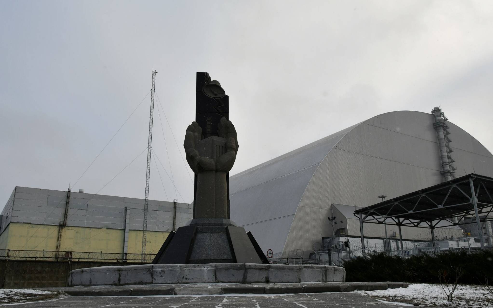 (FILES) This file photograph taken on December 8, 2020 shows a monument in front of the giant protective dome built over the sarcophagus of the destroyed fourth reactor of Chernobyl nuclear power plant. - Ukraine announced on February 24 that Russian forces had captured the Chernobyl nuclear power plant after a "fierce" battle on the first day of the Kremlin's invasion of its ex-Soviet neighbour. "After the absolutely senseless attack of the Russians in this direction, it is impossible to say that the Chernobyl nuclear power plant is safe. This is one of the most serious threats to Europe today," said Mykhailo Podolyak, advisor to the chief of the presidential administration. (Photo by GENYA SAVILOV / AFP)