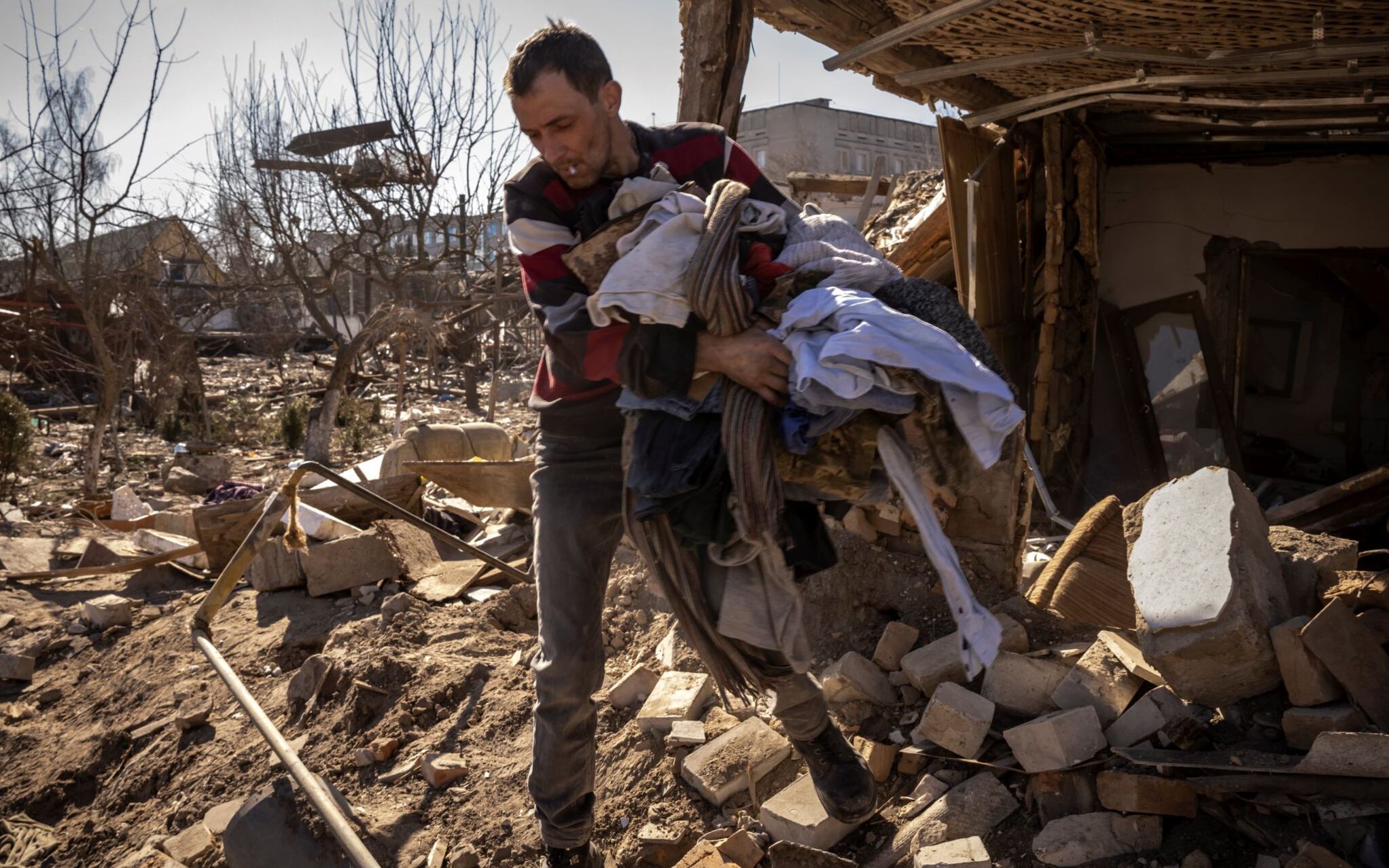 A man collects clothes from a damaged house in the city of Zhytomyr, northern Ukraine, on March 23, 2022. (Photo by FADEL SENNA / AFP)