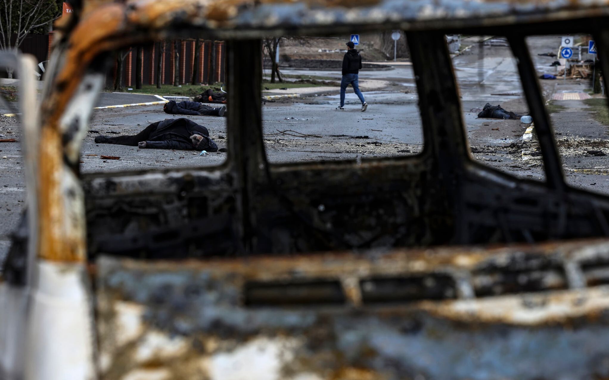 EDITORS NOTE: Graphic content / A man walks on a street with several dead bodies on the ground a street in Bucha, northwest of Kyiv, as Ukraine says Russian forces are making a "rapid retreat" from northern areas around Kyiv and the city of Chernigiv, on April 2, 2022. - The bodies of at least 20 men in civilian clothes were found lying in a single street Saturday after Ukrainian forces retook the town of Bucha near Kyiv from Russian troops, AFP journalists said. Russian forces withdrew from several towns near Kyiv in recent days after Moscow's bid to encircle the capital failed, with Ukraine declaring that Bucha had been "liberated". (Photo by RONALDO SCHEMIDT / AFP)