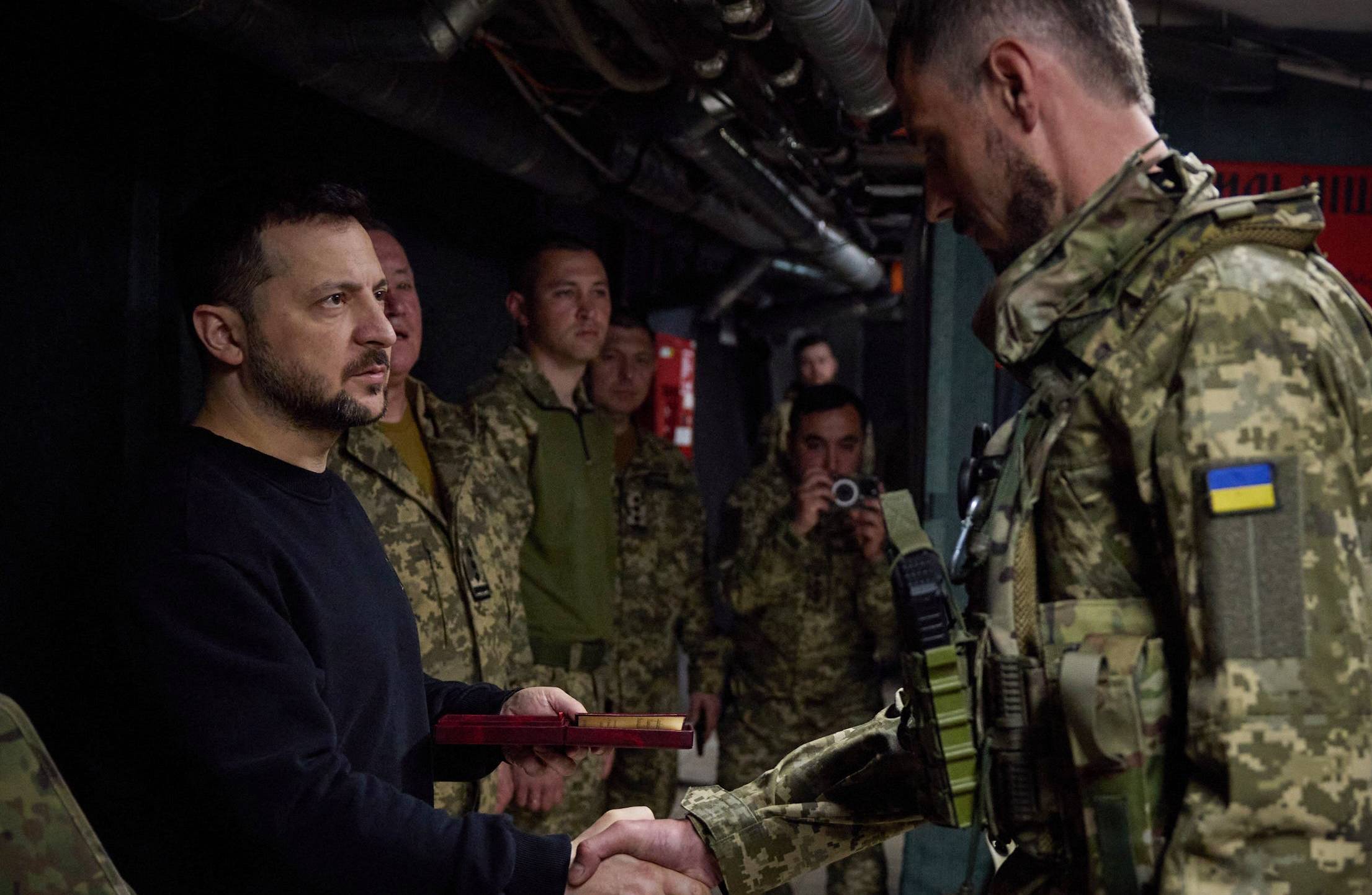 Mężczyzna w ciemnym stroju ściska rękę żołnoierzowi ukraińskiemu
