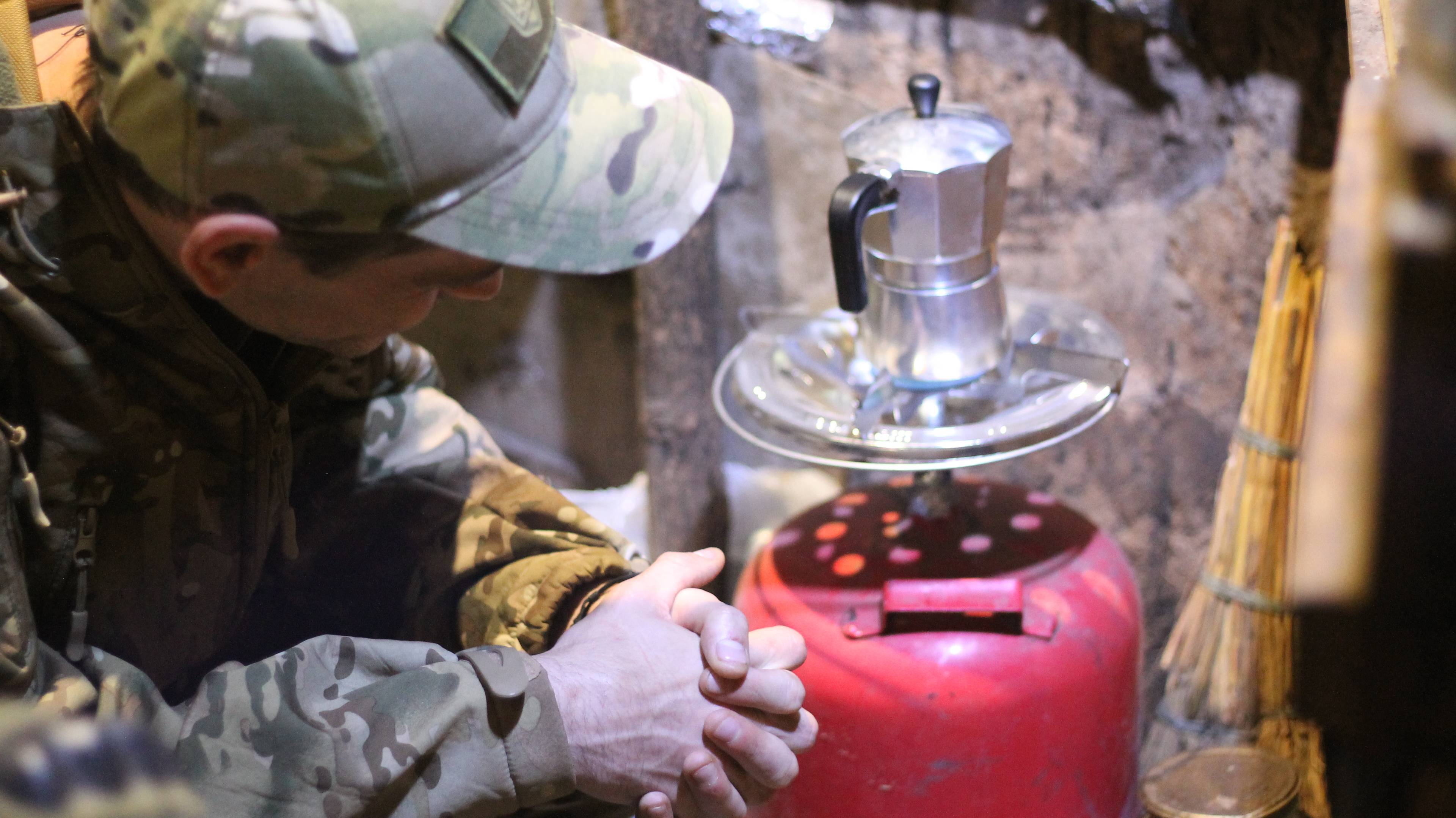 Ziemianka. Żołnierz pilnuje kawiarki, którą postawił na palniku butli gazowej.