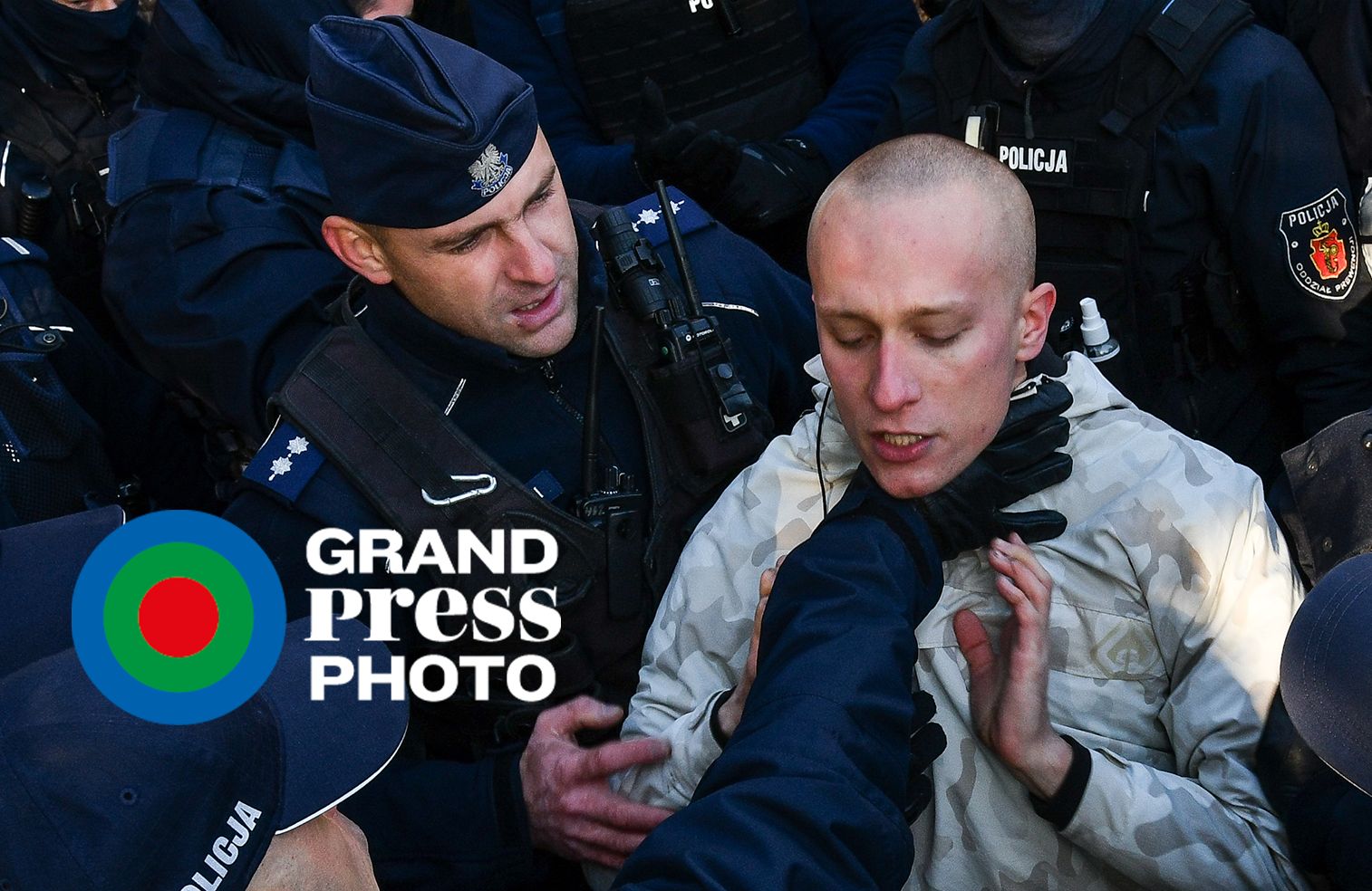 Policjant chwyta za gardło protestującego, otoczonego przez innych policjantów
