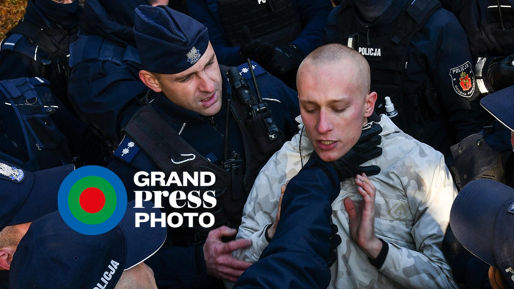 Policjant chwyta za gardło protestującego, otoczonego przez innych policjantów