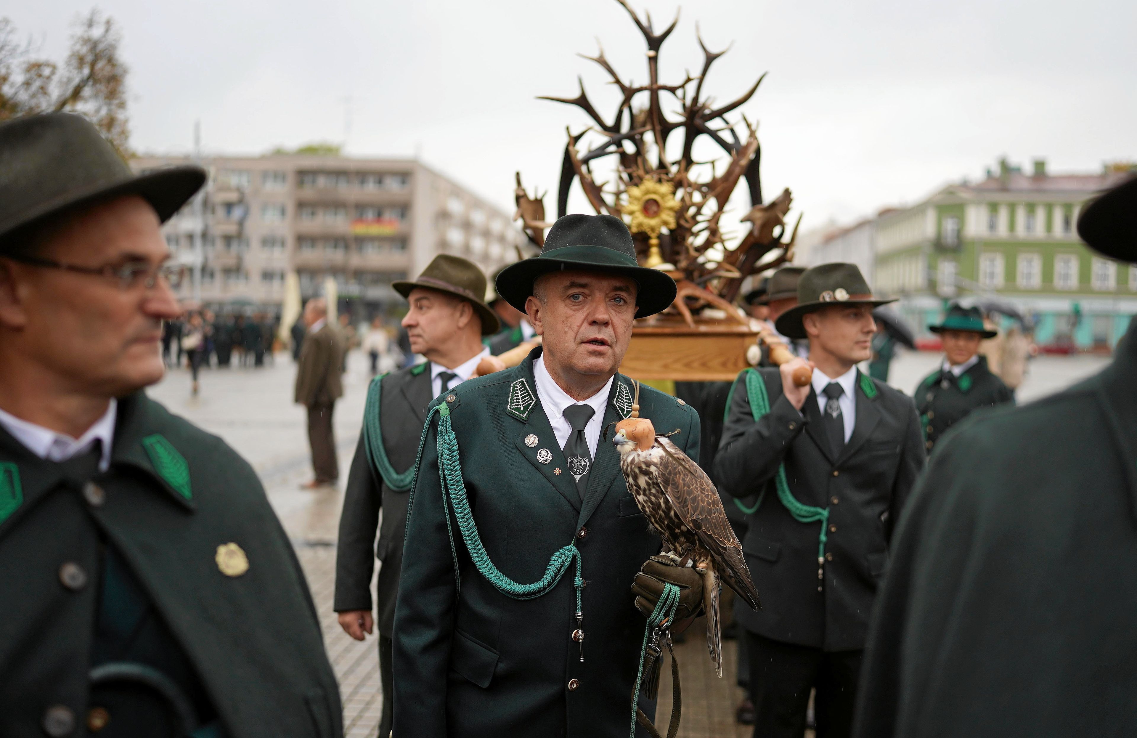 Myśliwi w zielonych mundurach niosą ołtarz z poroża