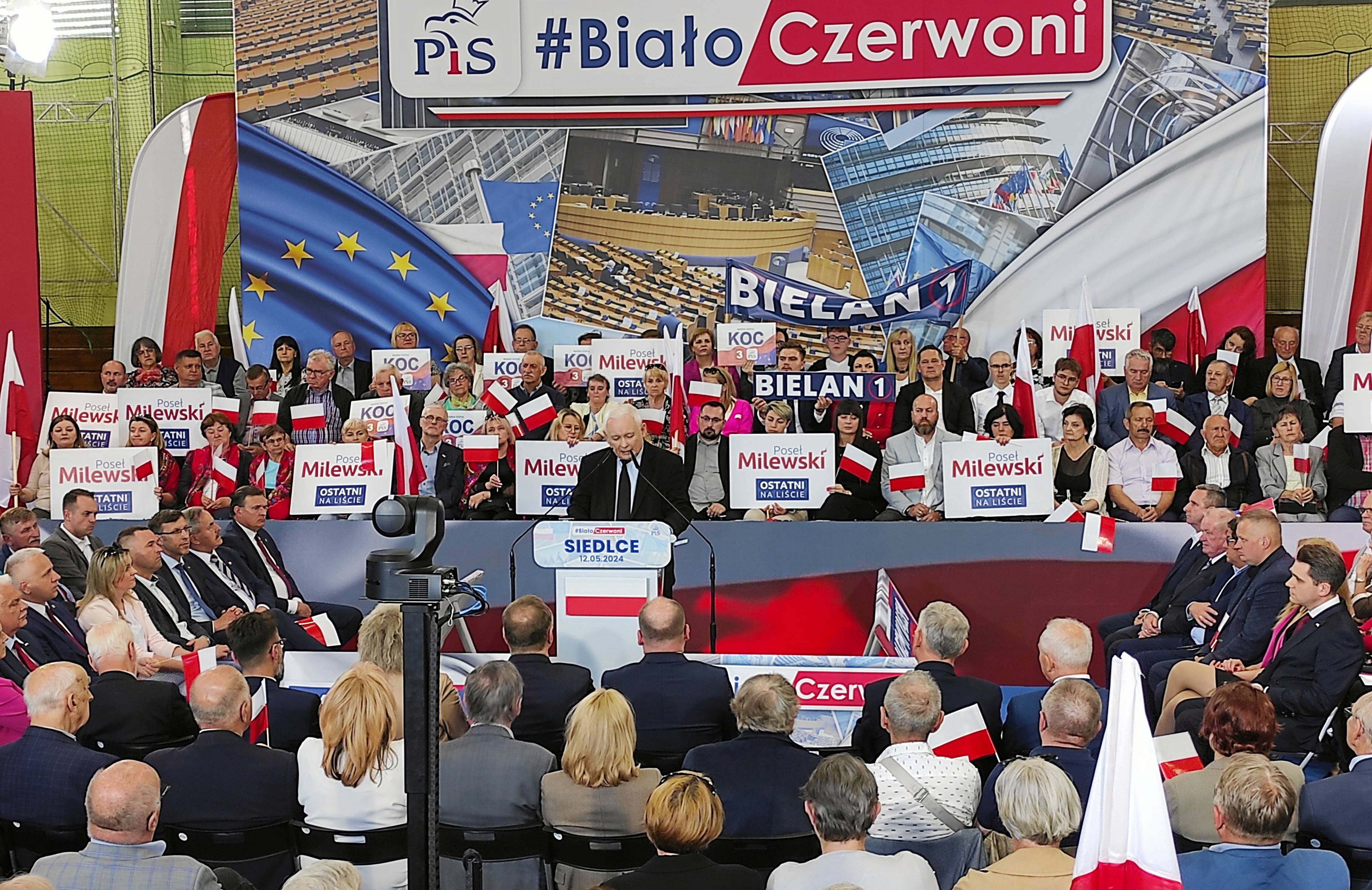 Jarosław Kaczyński, na pierwszym planie tłum ludzi, za nim transparent z napisem „#BiałoCzerwoni”