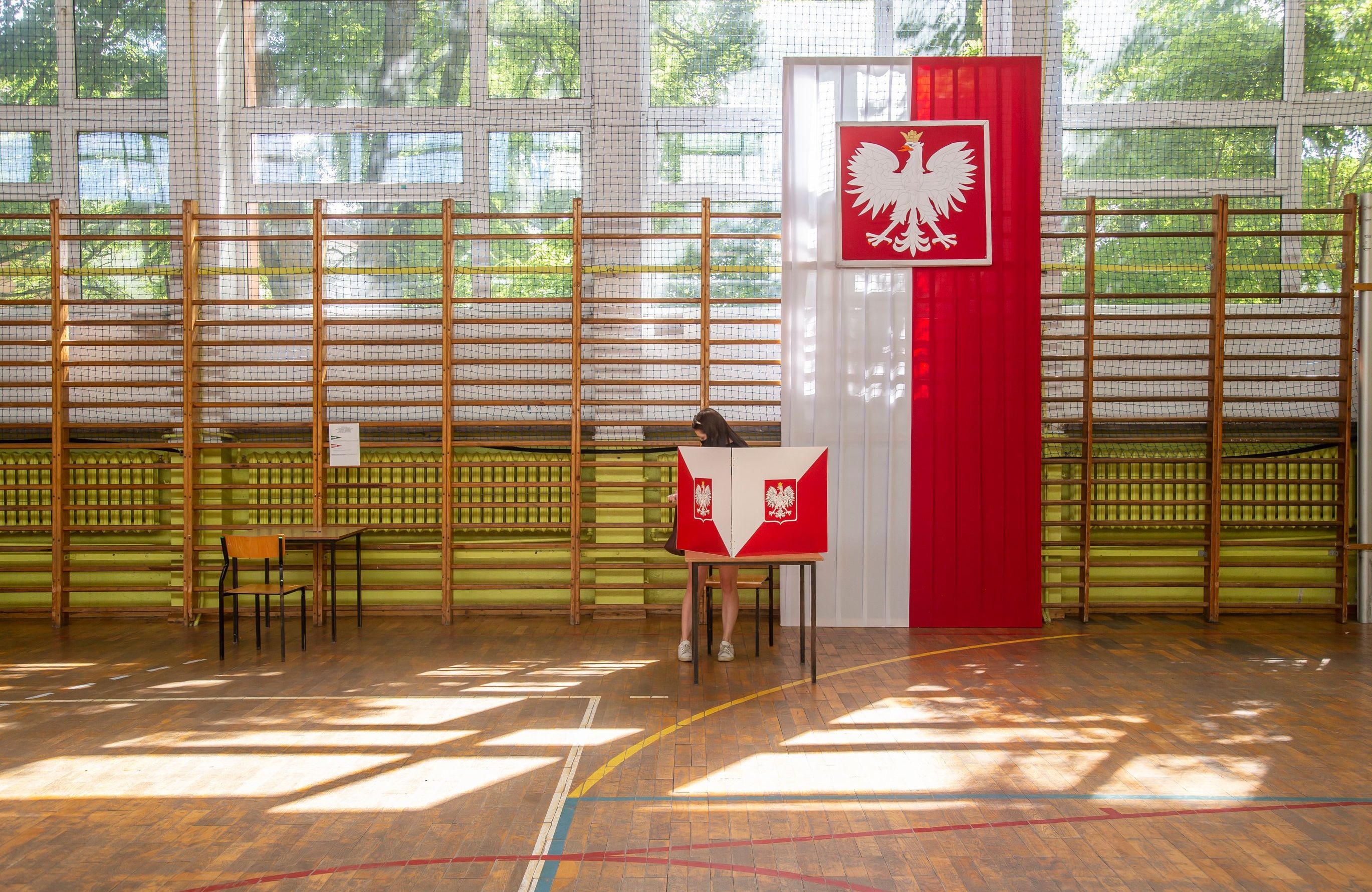 Sala szkolna, udekorowana flagą białoczerwoną, stolik do głosowania