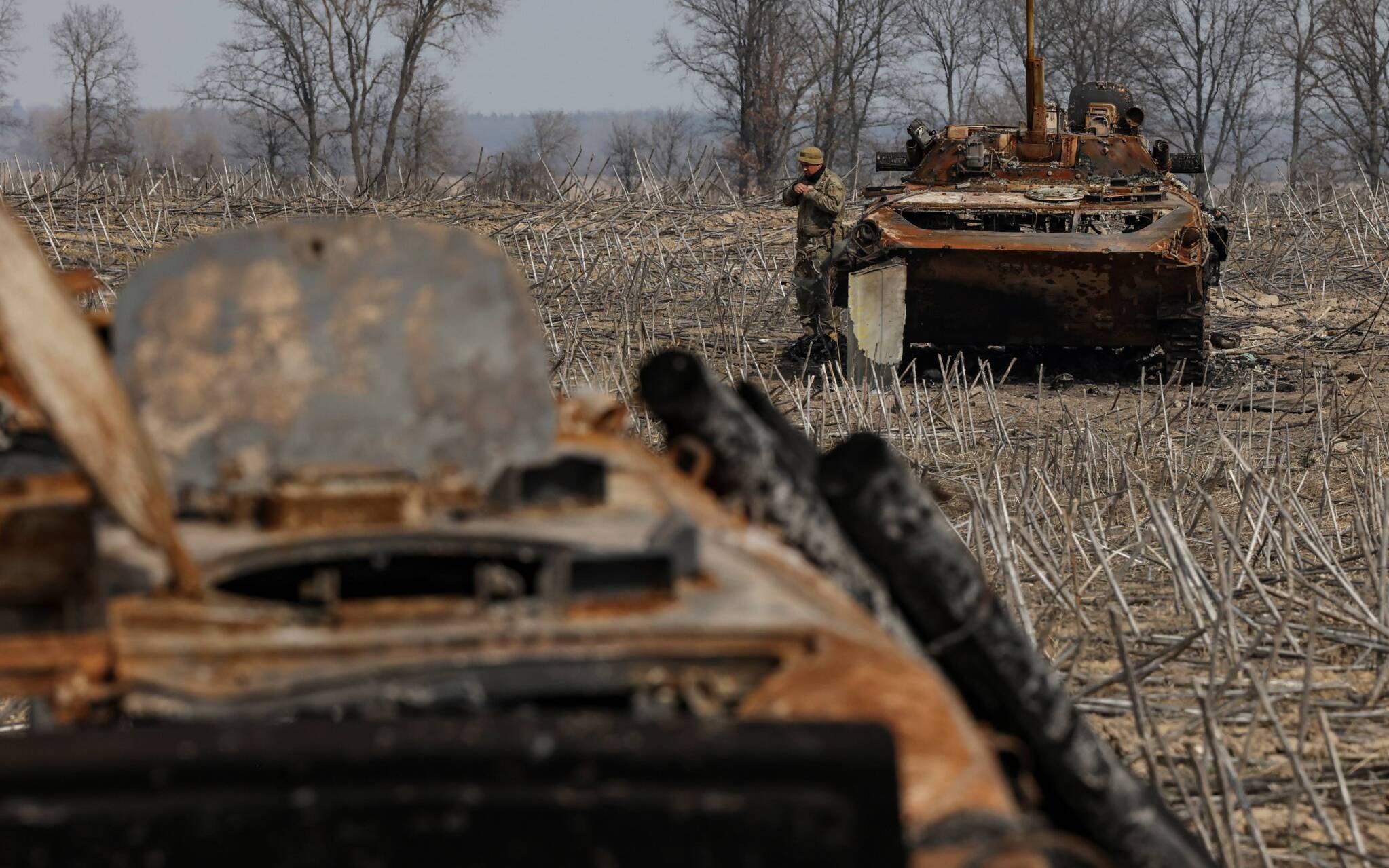 A Ukrainian soldier checks the wreckage of a burnt Russian tank on the outskirts of Kyiv, on March 31, 2022, amid Russian invasion of Ukraine. (Photo by RONALDO SCHEMIDT / AFP)