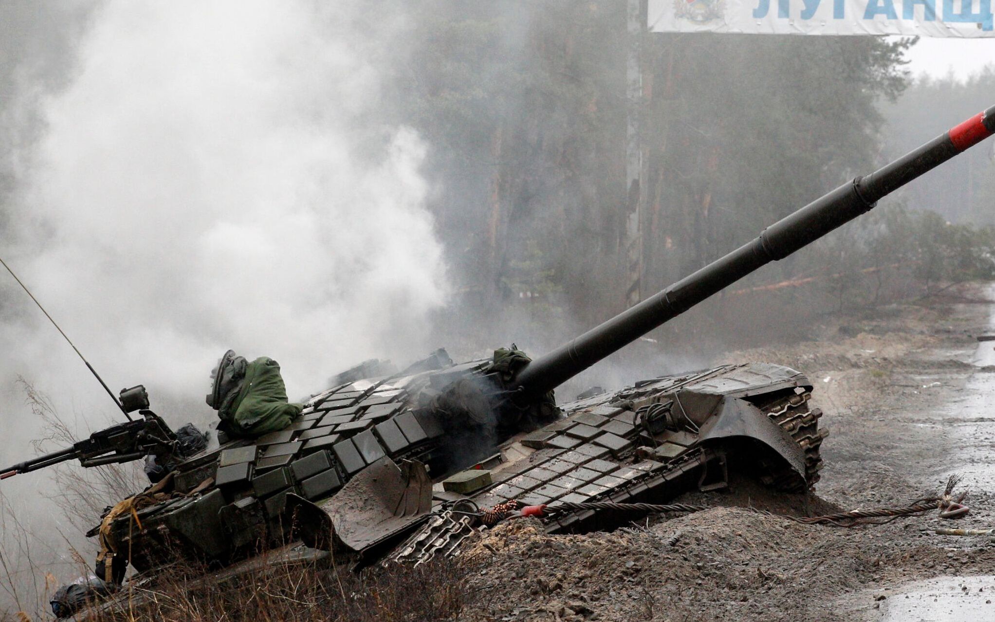 Smoke rises from a Russian tank destroyed by the Ukrainian forces on the side of a road in Lugansk region on February 26, 2022. - Russia on February 26 ordered its troops to advance in Ukraine "from all directions" as the Ukrainian capital Kyiv imposed a blanket curfew and officials reported 198 civilian deaths. (Photo by Anatolii Stepanov / AFP)