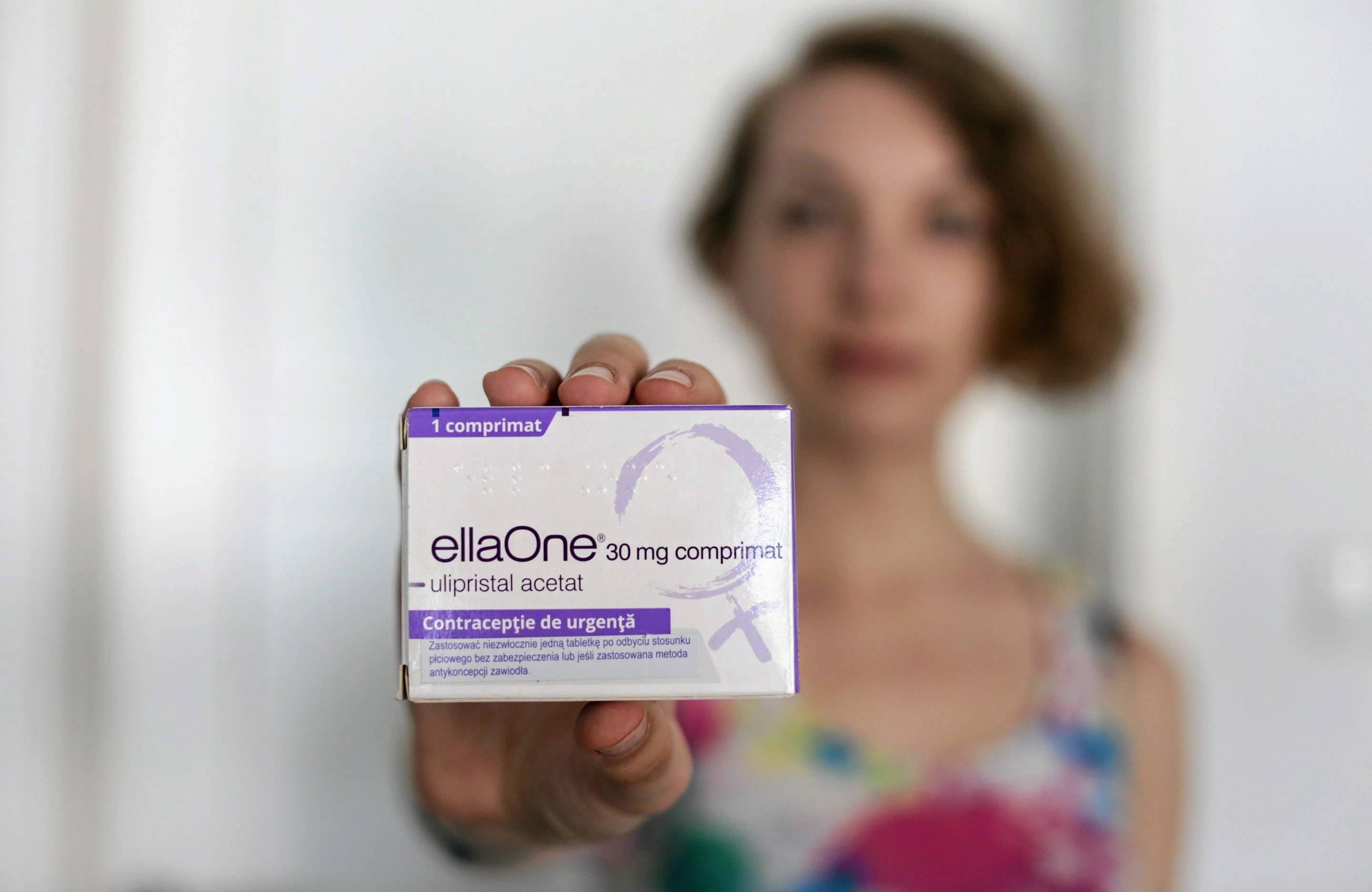 Kobieta trzyma przed sobą opakowanie tabletki EllaOne