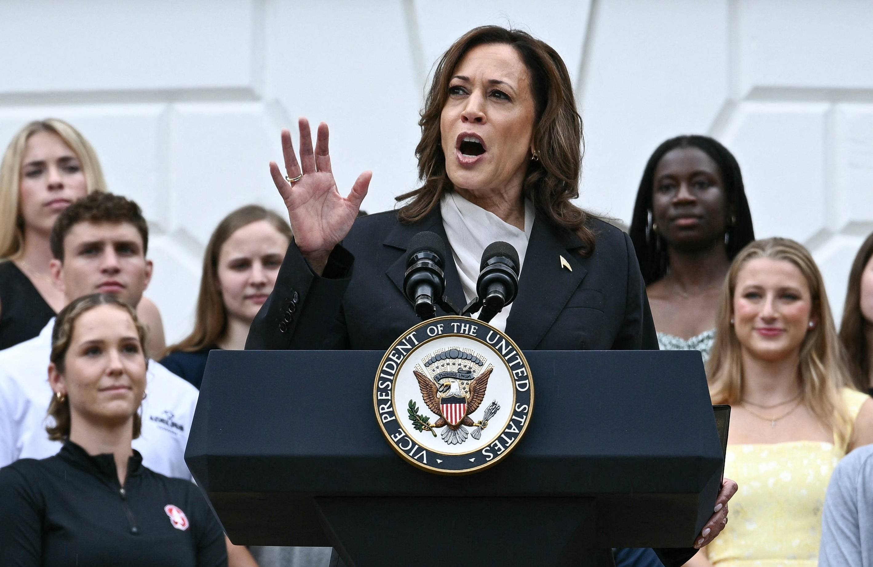 Kobieta o ciemnych włosach do ramion i ciemnej cerze (Kamala Harris) przemawia z podium z logo wiceprezydenta USA