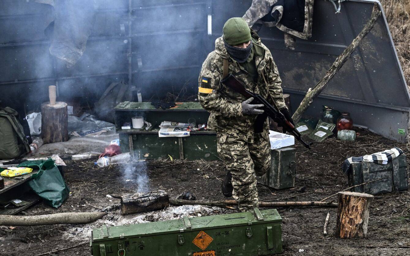 An Ukrainian soldier walks next to a camp fire at a frontline, northeast of Kyiv on March 3, 2022. - A Ukrainian negotiator headed for ceasefire talks with Russia said on March 3, 2022, that his objective was securing humanitarian corridors, as Russian troops advance one week into their invasion  of the Ukraine. (Photo by Aris Messinis / AFP)