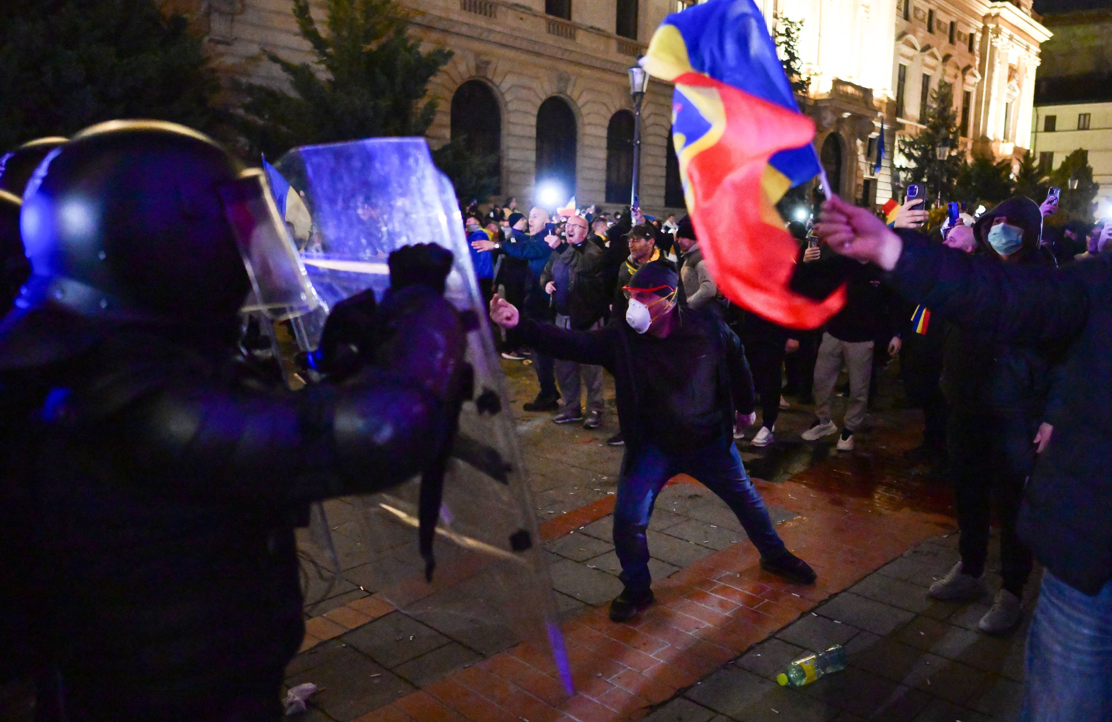 Noc. Protestujący z rumuńską flagą (żółto-czerowno-niebieską) i policjanci z tarczami