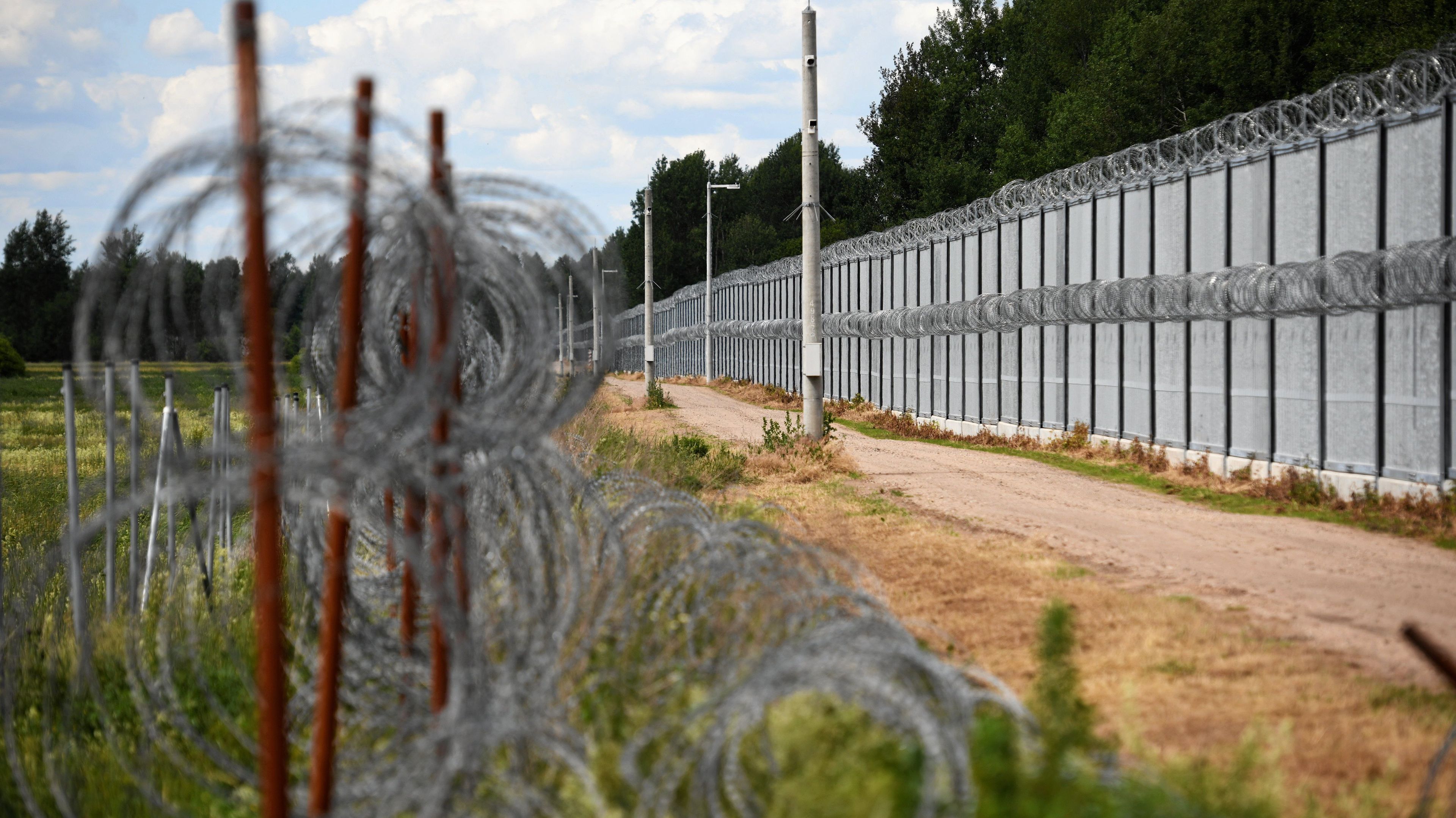 Granica z żelaznym płotem i spiralami drutu żyletkowego