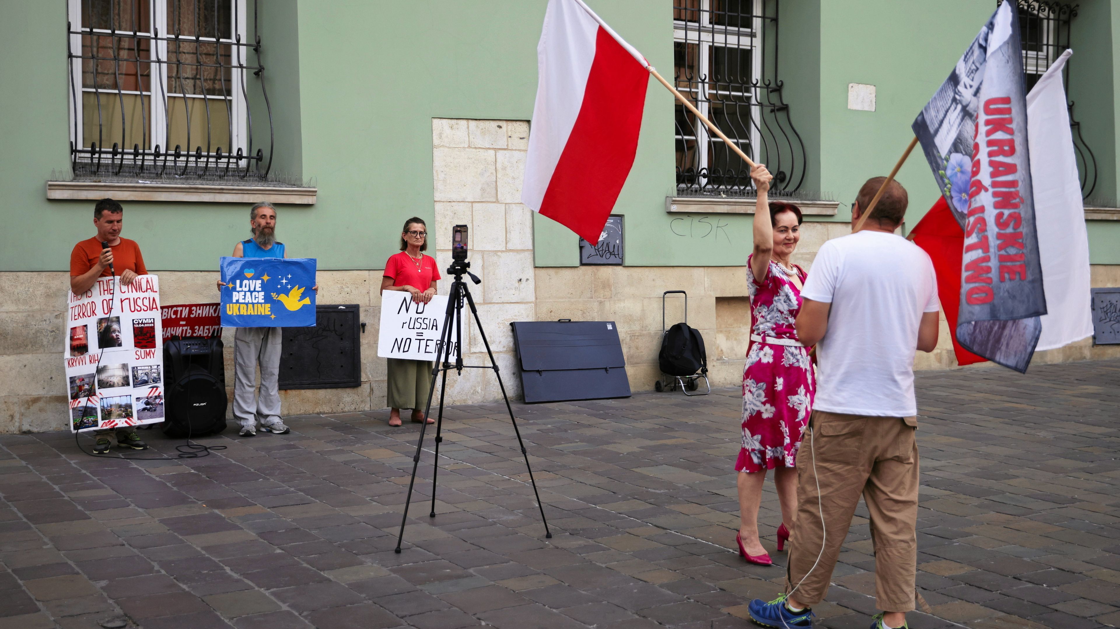 Ludzie z polskimi flagami i hasłami o „ukraińskim ludobójstwie" zasłaniają na ulicy trzy osoby z hasłami proukraińskimi.
