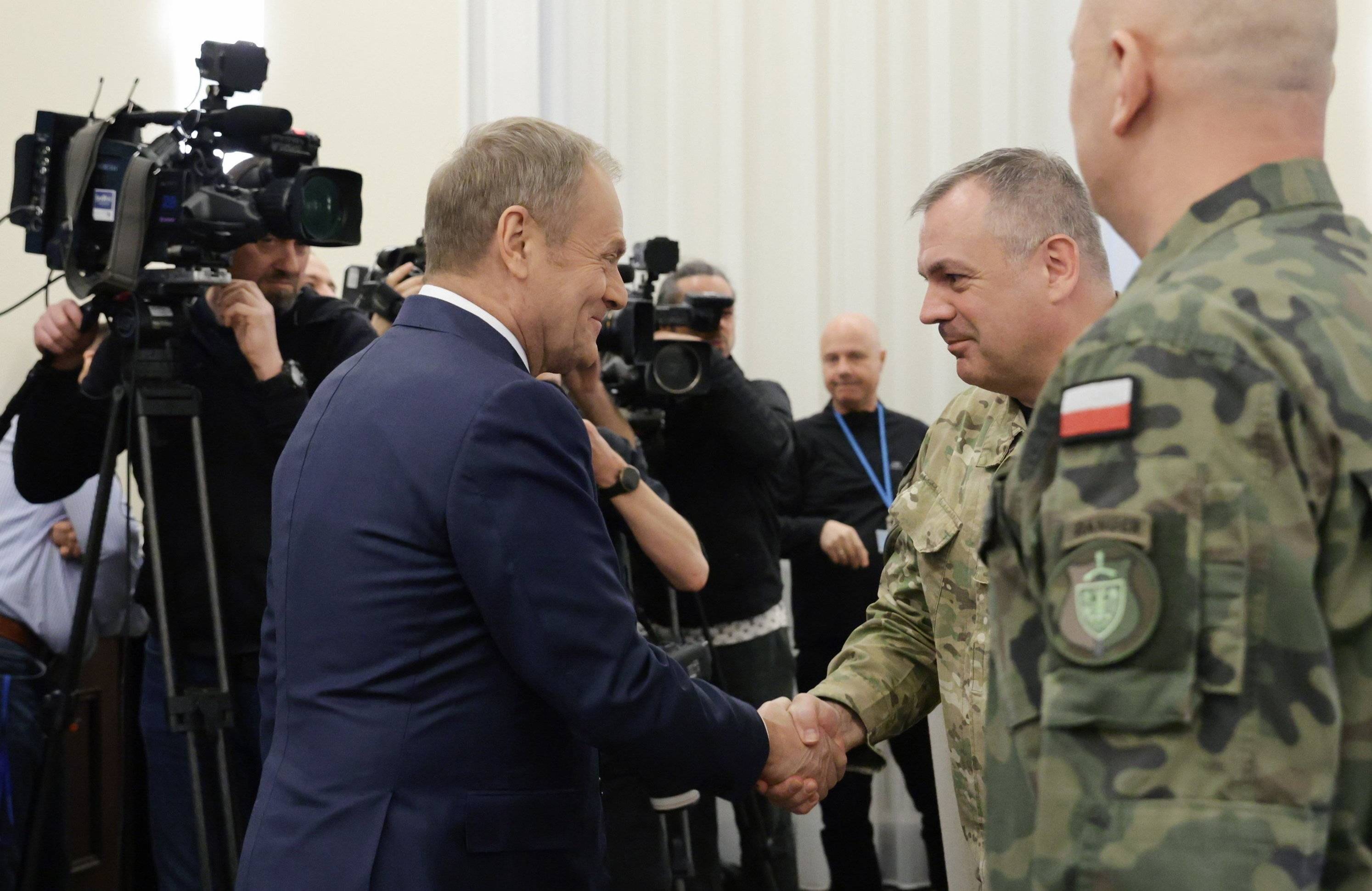 Premier Donald Tusk ściska dłoń wojskowego podczas posiedzenia Rady Ministrów