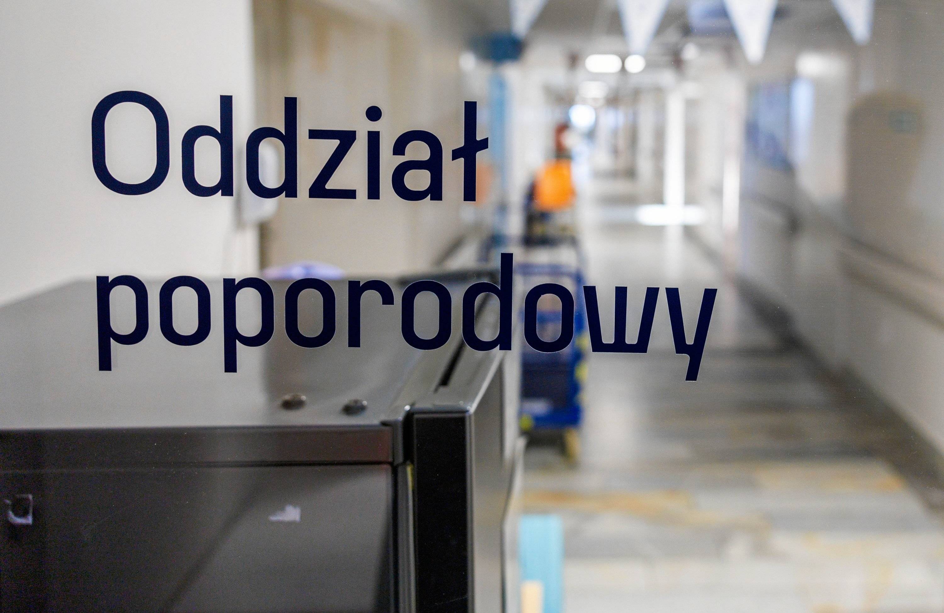 Szyba z napisem Oddział porodowy. W tle korytarz