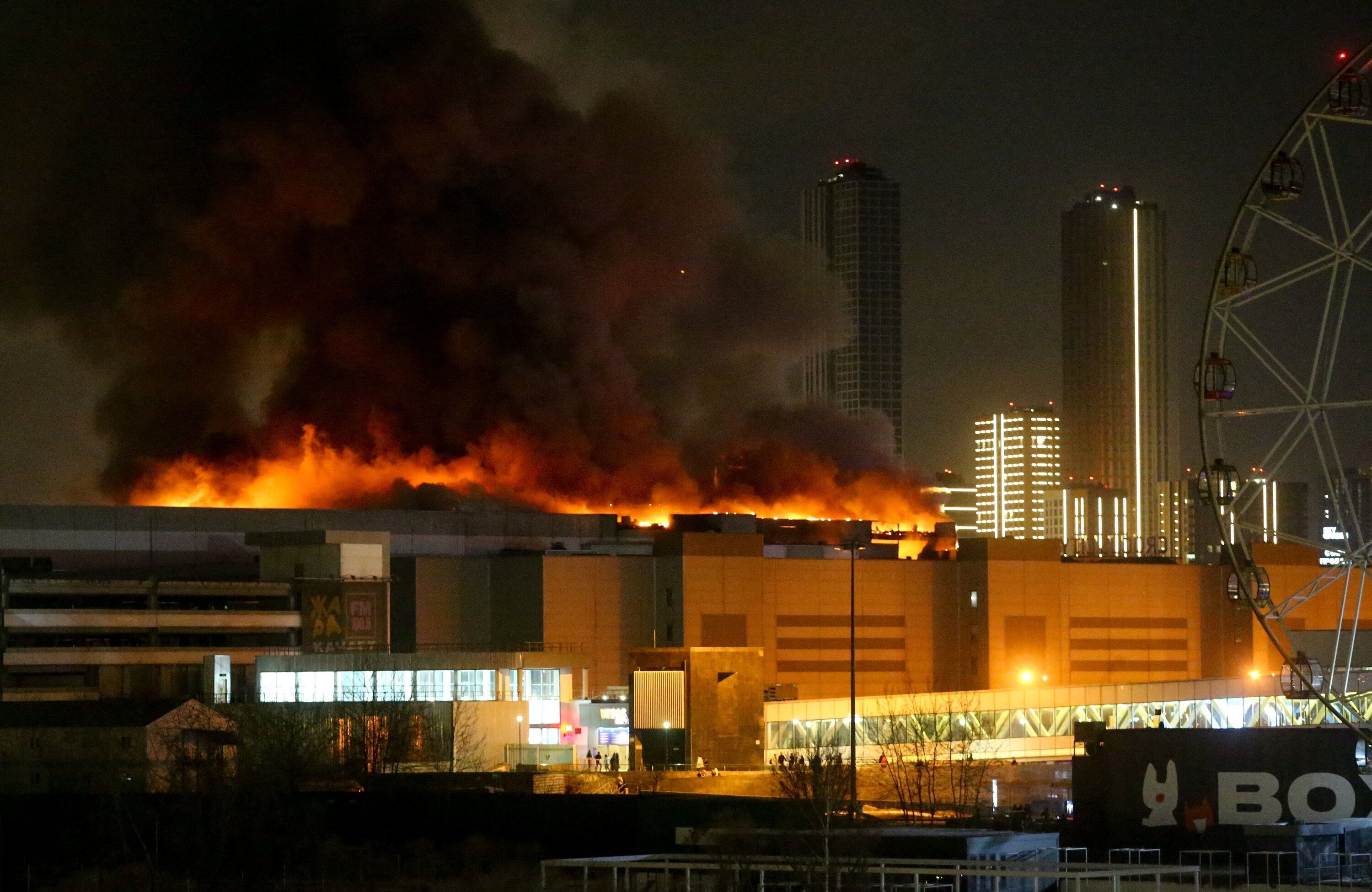 Płonące centrum handlowe, płomienie i dym widać nad dachem, rozświetlają noc