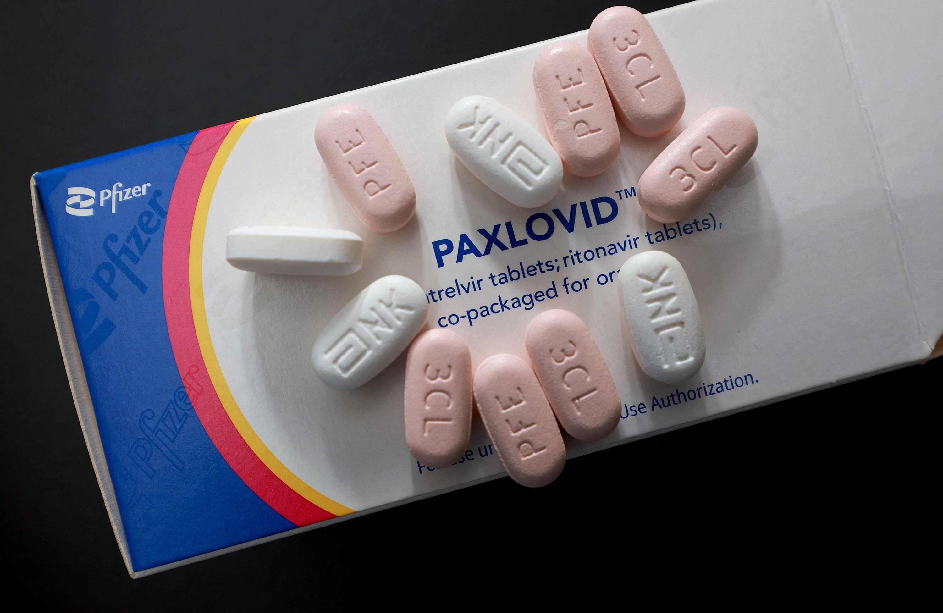 Opakowanie leku Paxlovid, na nim białe i różowe tabletki