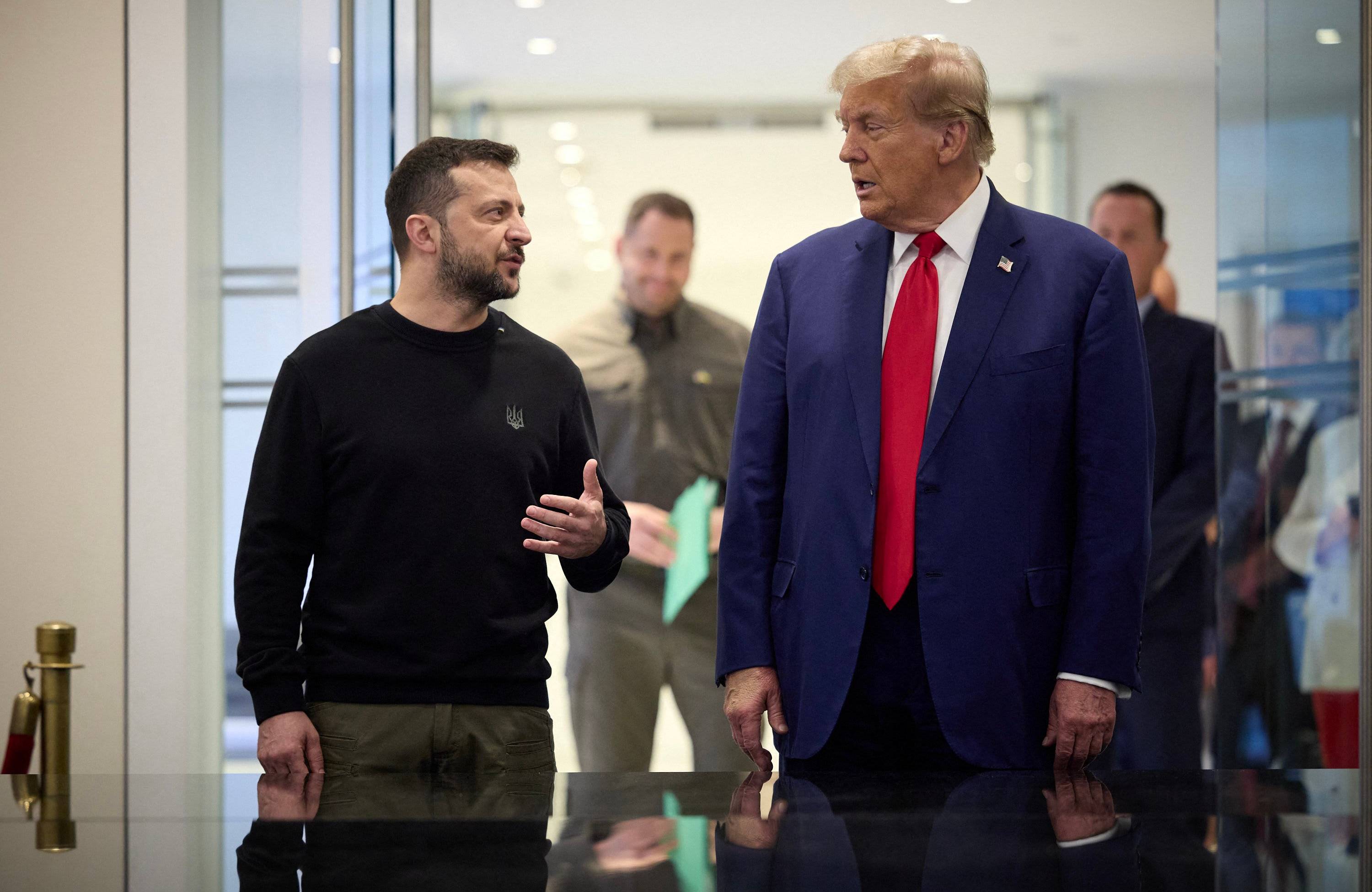 Dwaj mężczyźni spoglądają na siebie, po lewej prezydent Ukrainy Wołodymyr Zełenski w wojskowej bluzie, po prawej prezydent USA Donald Trump w garniturze i czerwonym krawacie