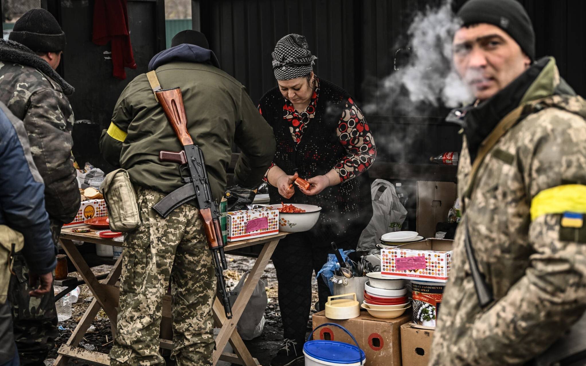 A woman cooks for Ukrainian soldiers at a frontline, northeast of Kyiv on March 3, 2022. - A Ukrainian negotiator headed for ceasefire talks with Russia said on March 3, 2022, that his objective was securing humanitarian corridors, as Russian troops advance one week into their invasion  of the Ukraine. (Photo by Aris Messinis / AFP)