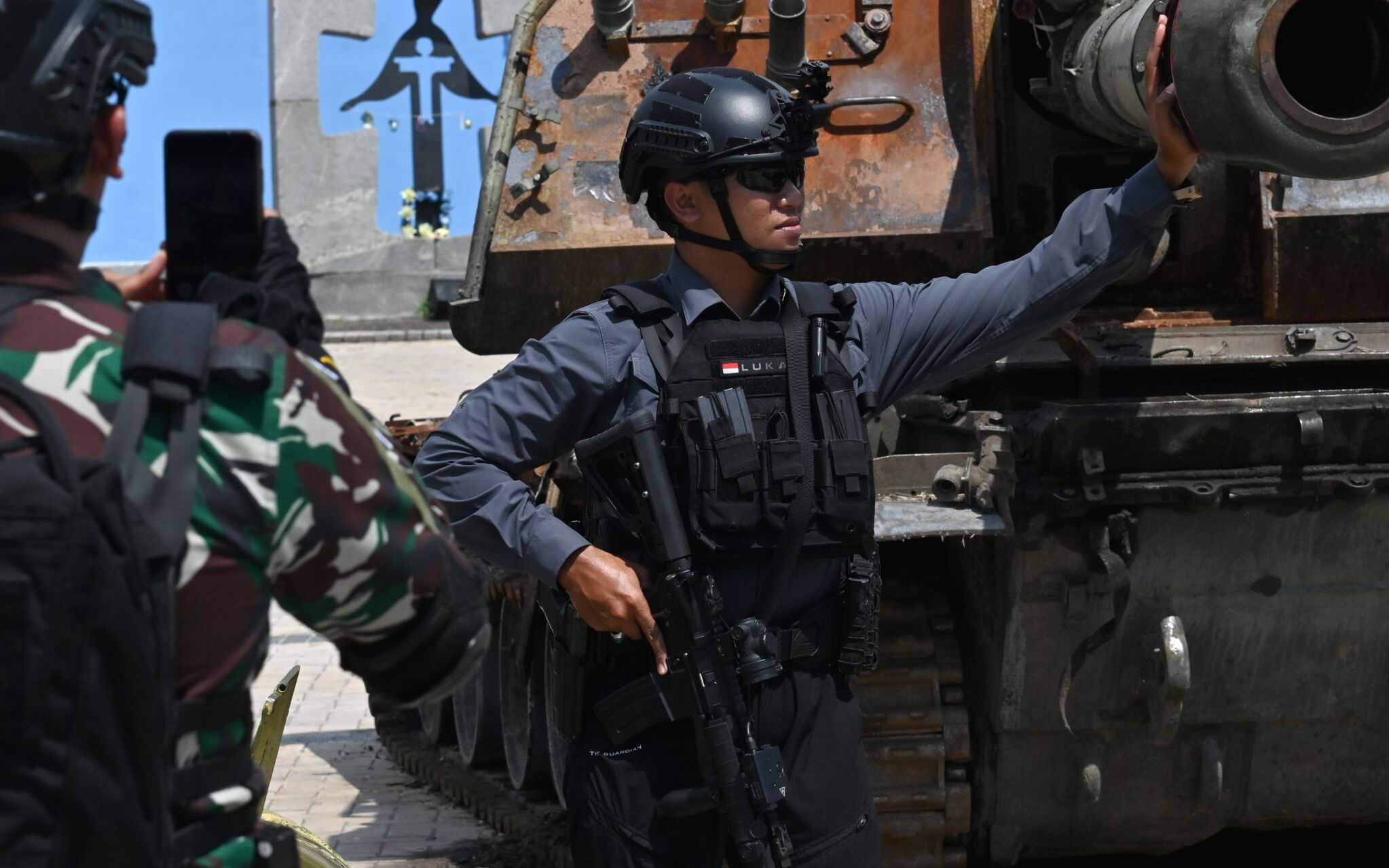 Security guard men of Indonesian President Joko Widodo, who is visiting Ukraine, pose for a picture next to a propelled artillery gun which is exhibited in the center of the Ukrainian capital Kyiv, amid the Russian invasion of Ukraine, on June 29, 2022. (Photo by Sergei SUPINSKY / AFP)